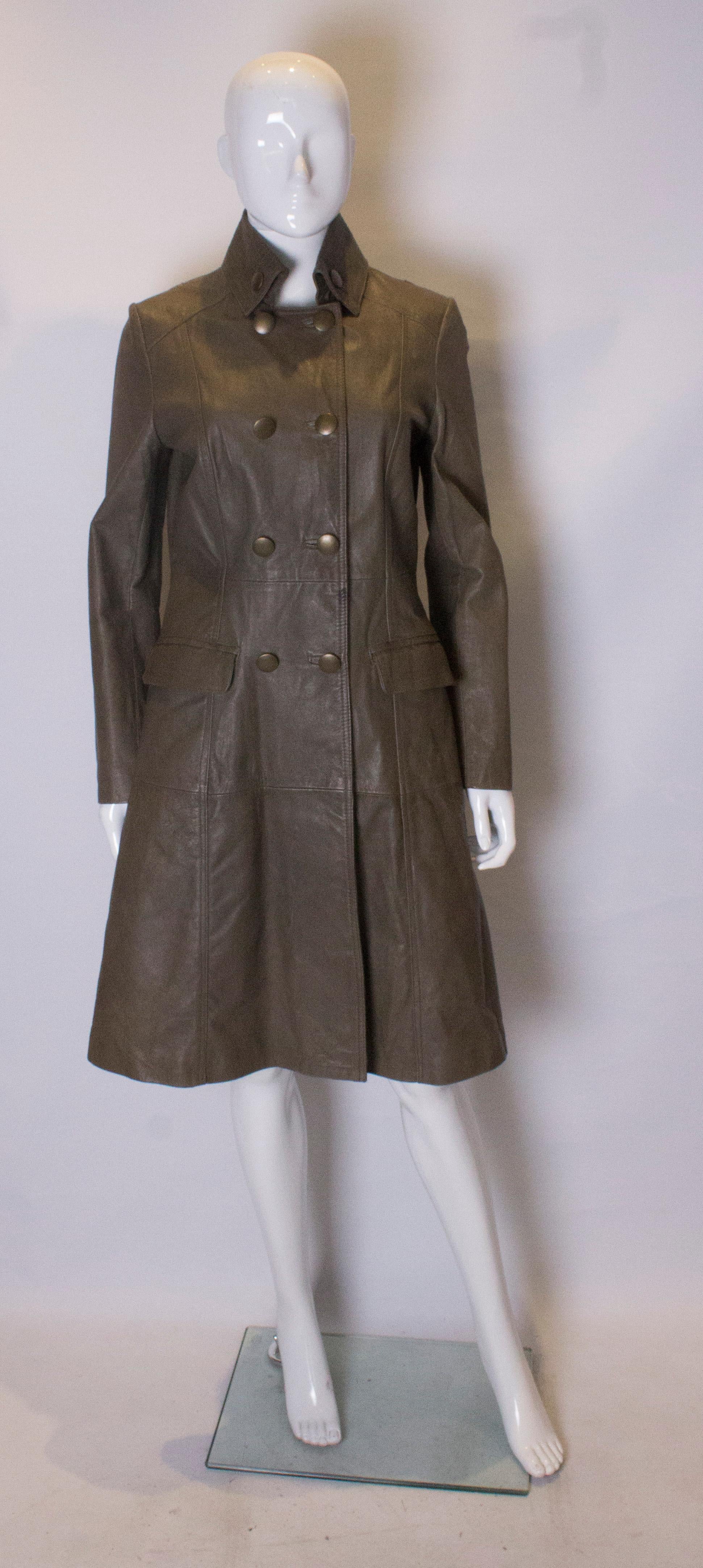 A smart leather coat in an olive green colour.  The coat has a button down collar with stitch detail, with a half belt at the back. It has a three button detail on the cuff and is double breasted, with two pockets  at the front. The coat is fully