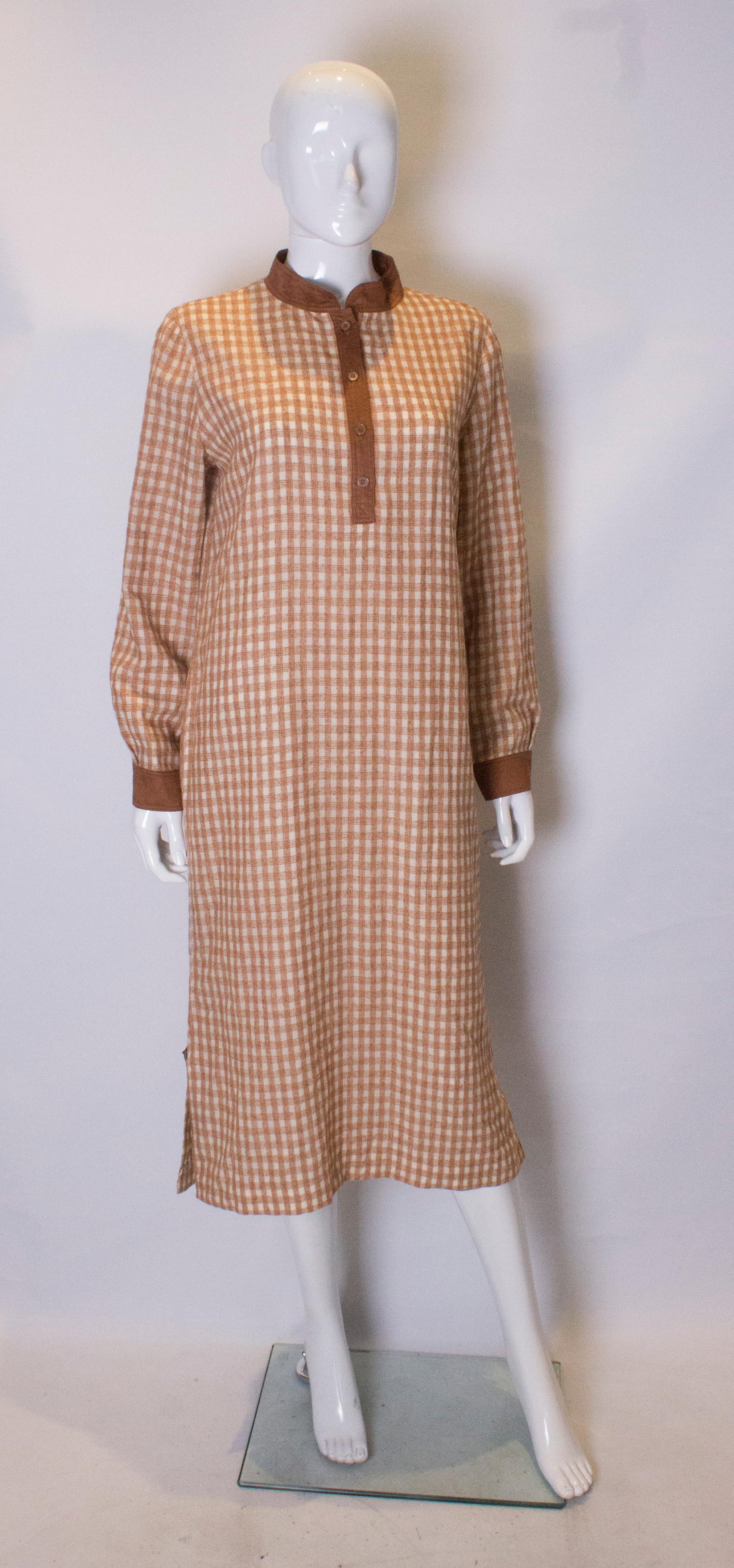 A chic vintage Courreges shirt dress. The dress is in brown and white check with brown cotton  edging. It has a 12'' slit on either side with a button fastening.The dress is fully lined.