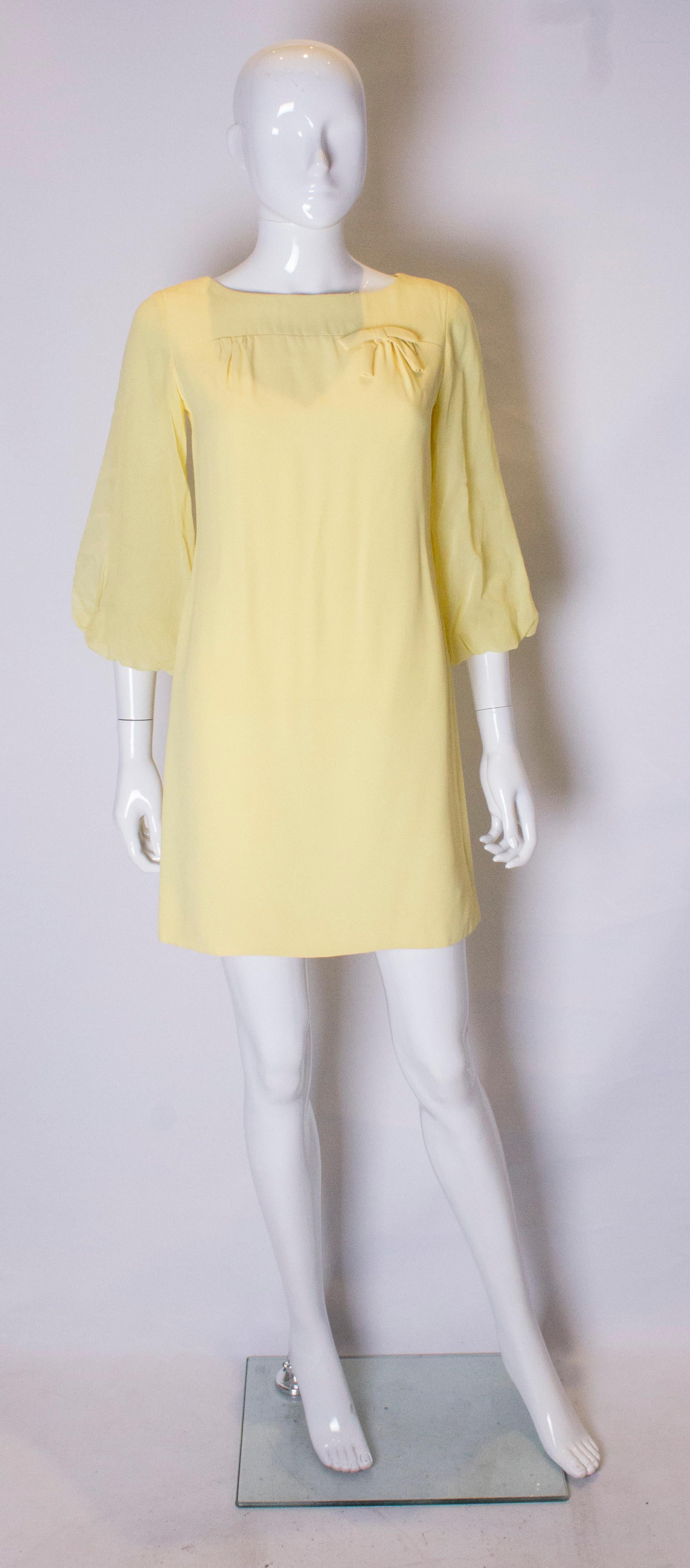  A pretty yellow mini dress with great sleaves. The dress is shift shape, and fully lined with a central back zip. It has a round neckline, and sheer bell sleaves which are elbow length.