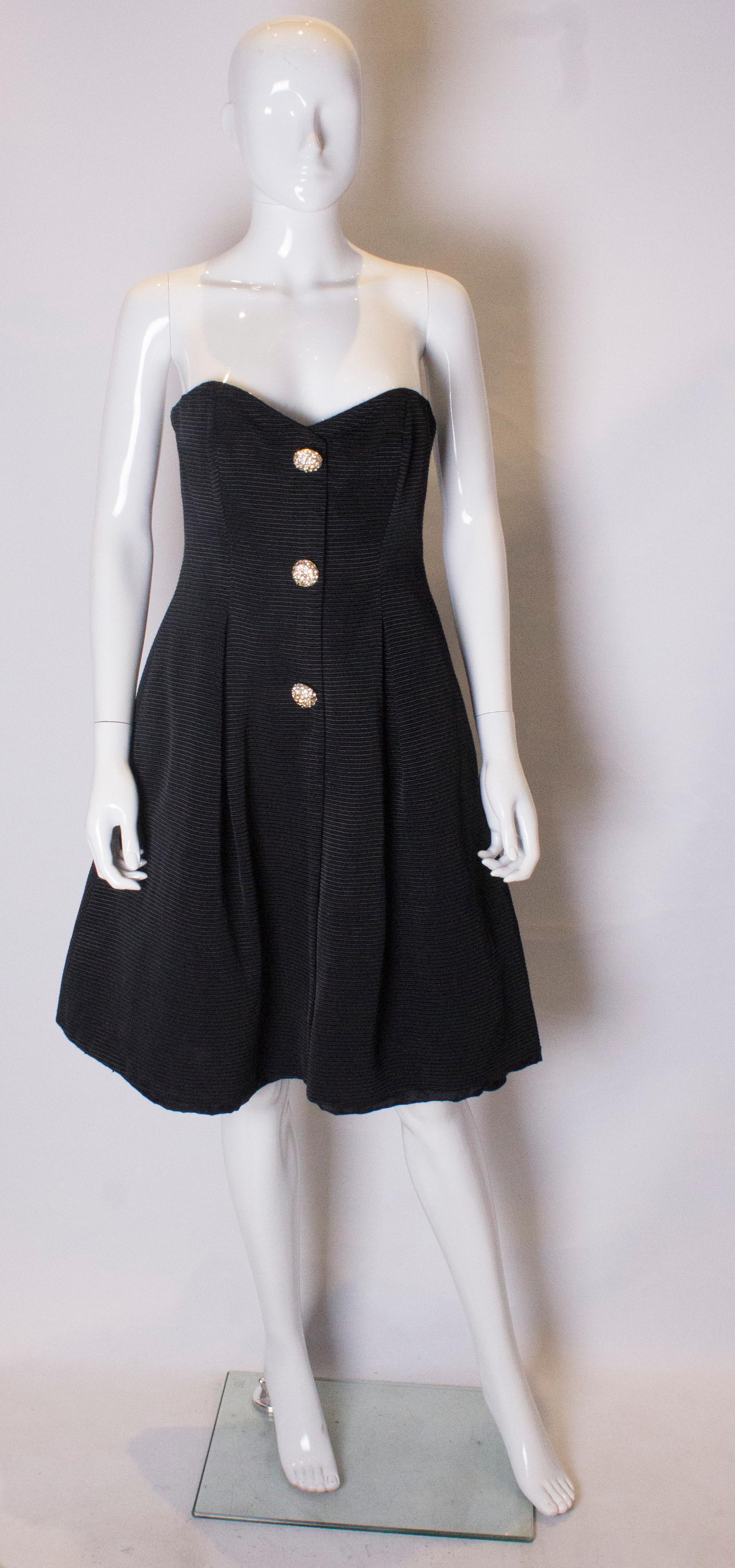 A stunning black grossgrain cocktail dress with wonderful buttons and matching shrug.  The dress is strapless with a central back zip , full net underskirt and is fully lined. The shrug has a shawl collar and cleverly connects over the buttons at