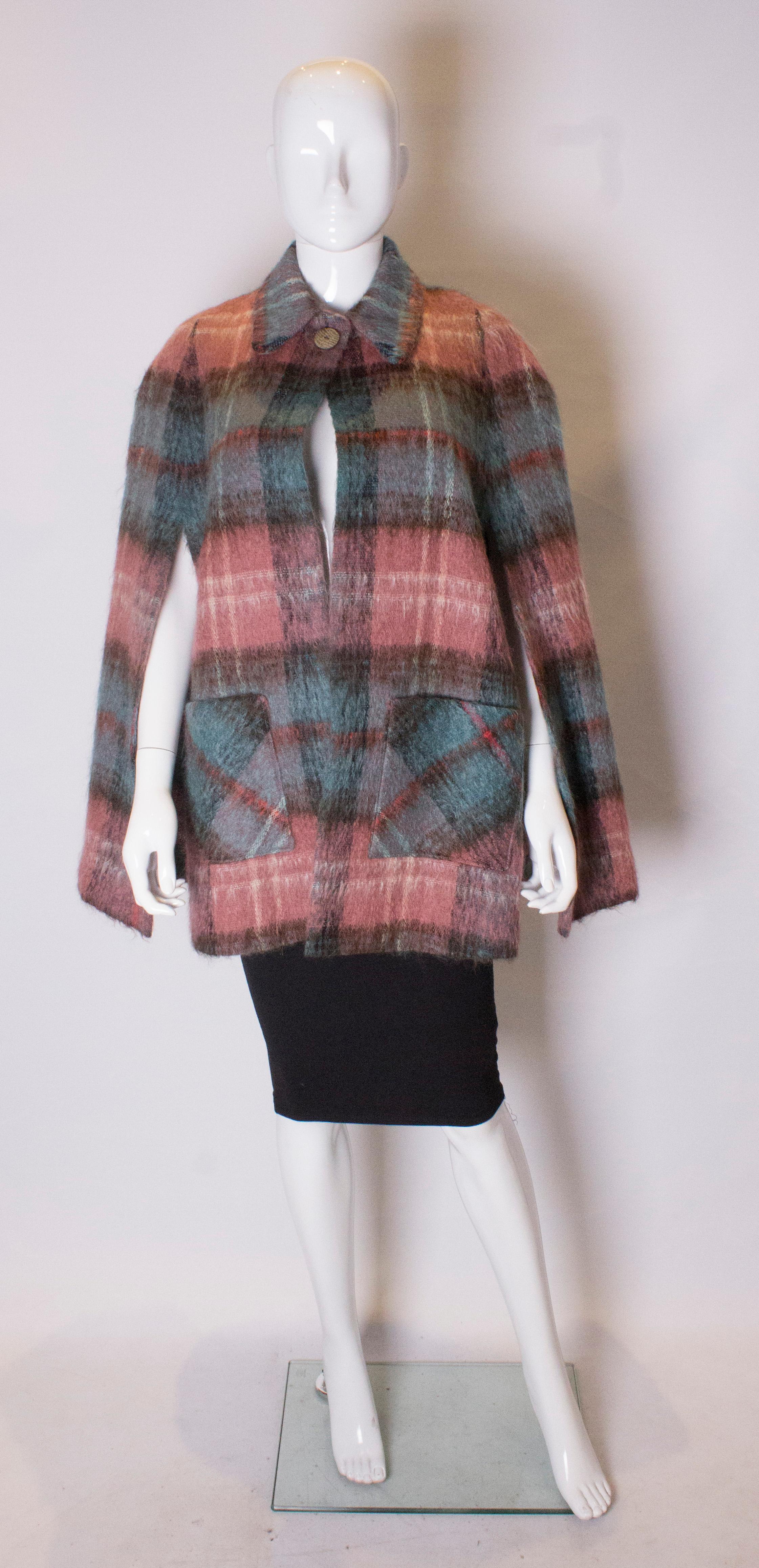 A pretty cape for Fall  by Andrew Stewart. The cape is in a pretty mix of turquoise and pink and has two front pockets and two arm slits.
Measurements , shoulder to shoulder 22'' , length 31''  Fabric 40% mohair, 60% wool