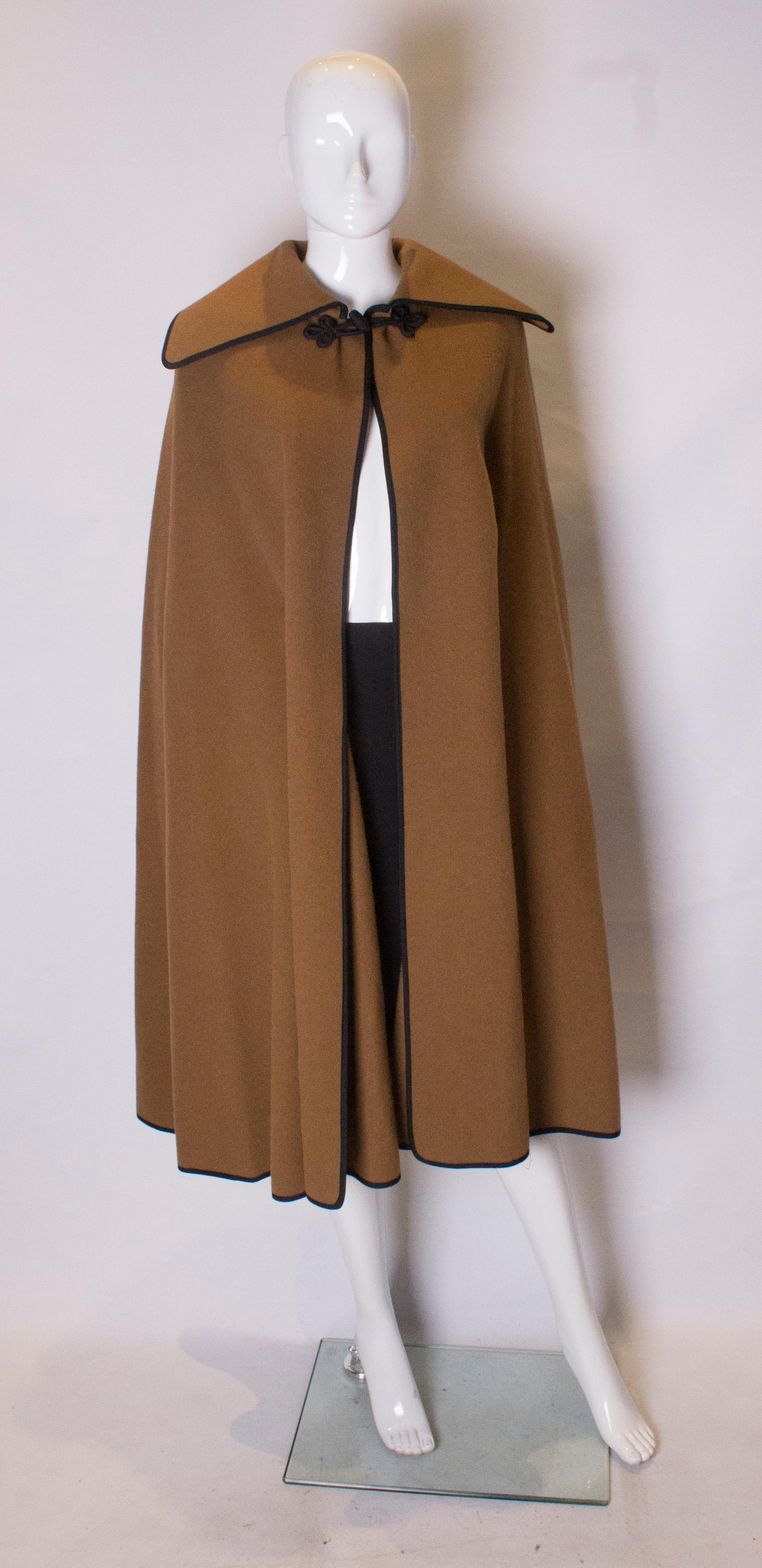A  great vintage cape by Jaeger.  The cape is 85% wool and 15 % camel hair, it is caramel colour with black braiding around the collar and fastening. Measurements: shoulder to shoulder 20'', length 44''