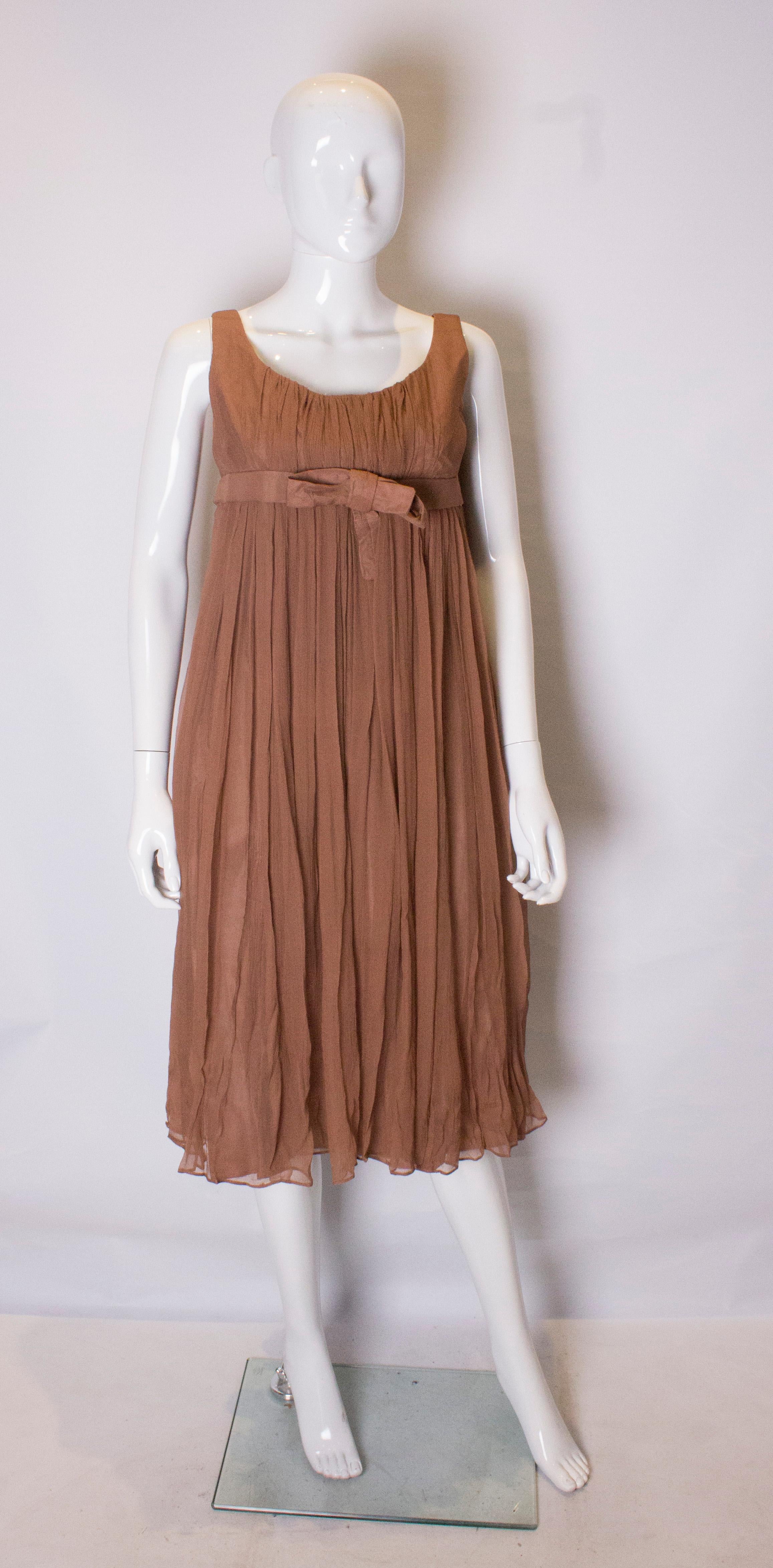 A chic vintage silk dress by Bernard Freres. The dress is in a pretty brown colour with a scoop neckline and a decorative band under the bust. It is fully lined with a central back zip .