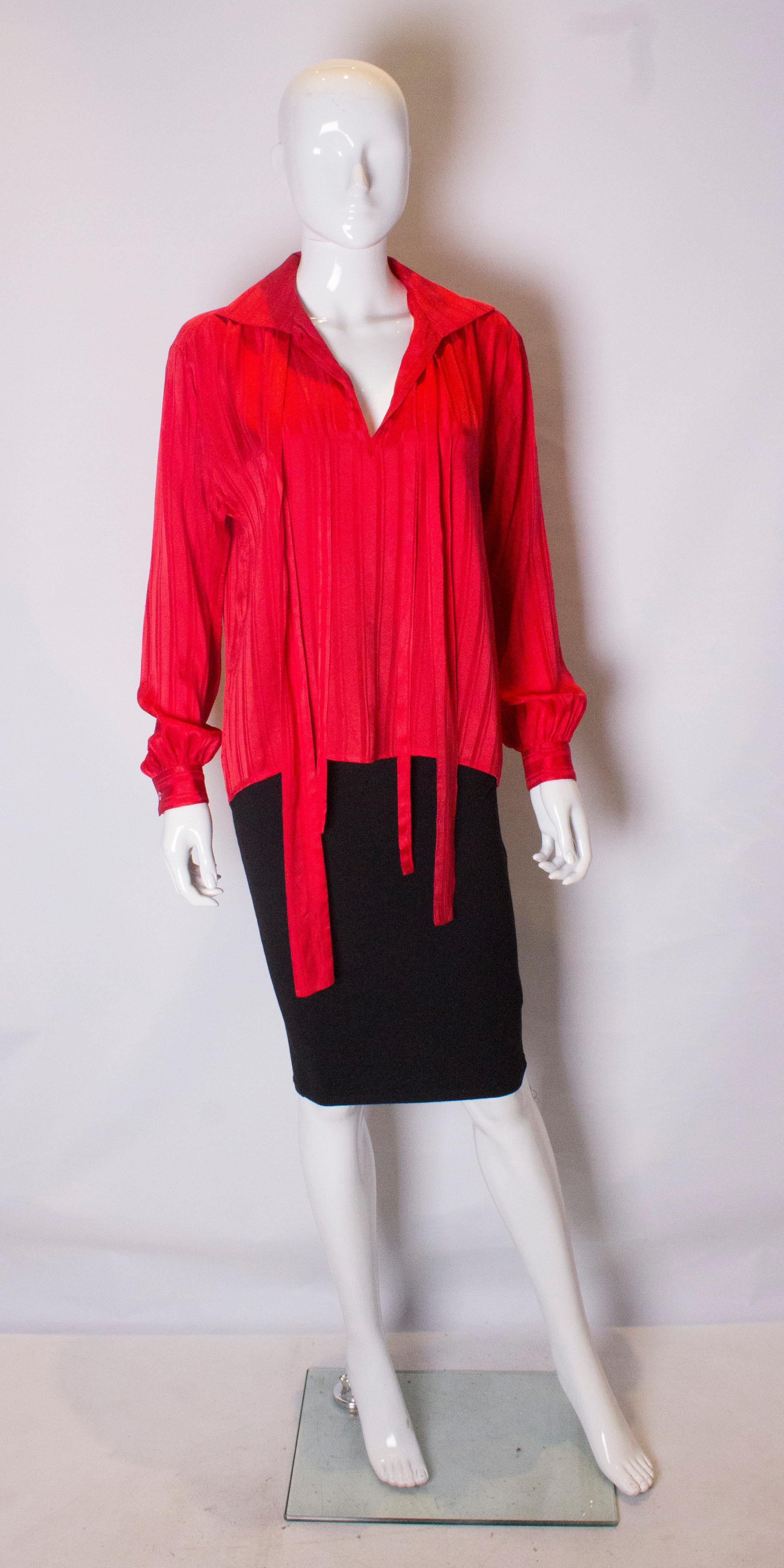 A cut red silk blouse by Yves Saint Laurent Rive Gauche line. The blouse is in a red self  stripe silk, and has a v neckline, single button cuffs and gathering from the yoke at the back.
