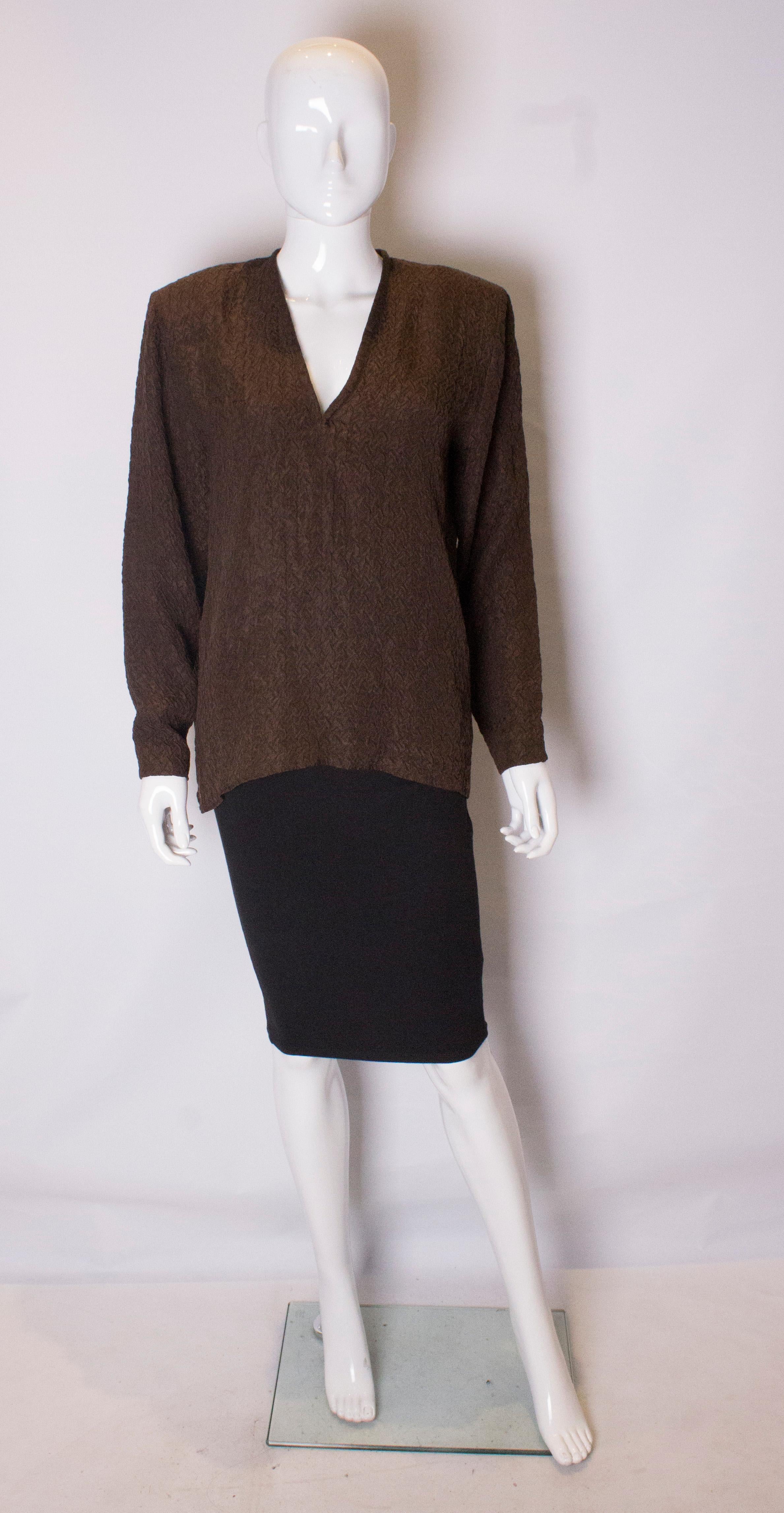 A great silk blouse by Yves Saint Laurent rive Gauche line . In a brown textured crinkle silk, the blouse has a v neckline and small shoulder pads.