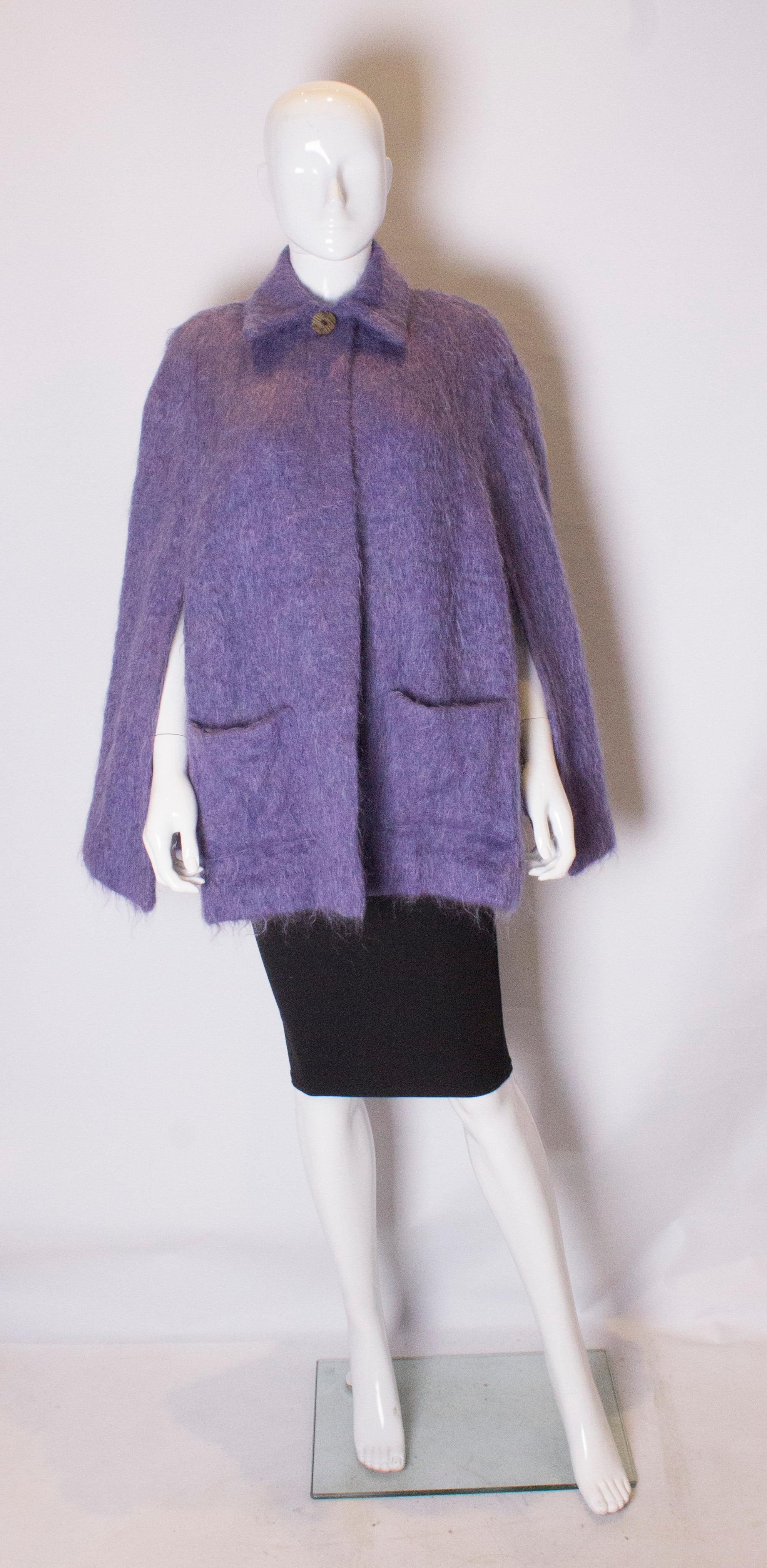 A pretty cape for the party season , by Andrew Stewart. The cape is in a lovely lavender colour, and has a popper fastening at the neck with two slit and two pockets at the front. Measurements; Shoulder to shoulder 20'', length 31''