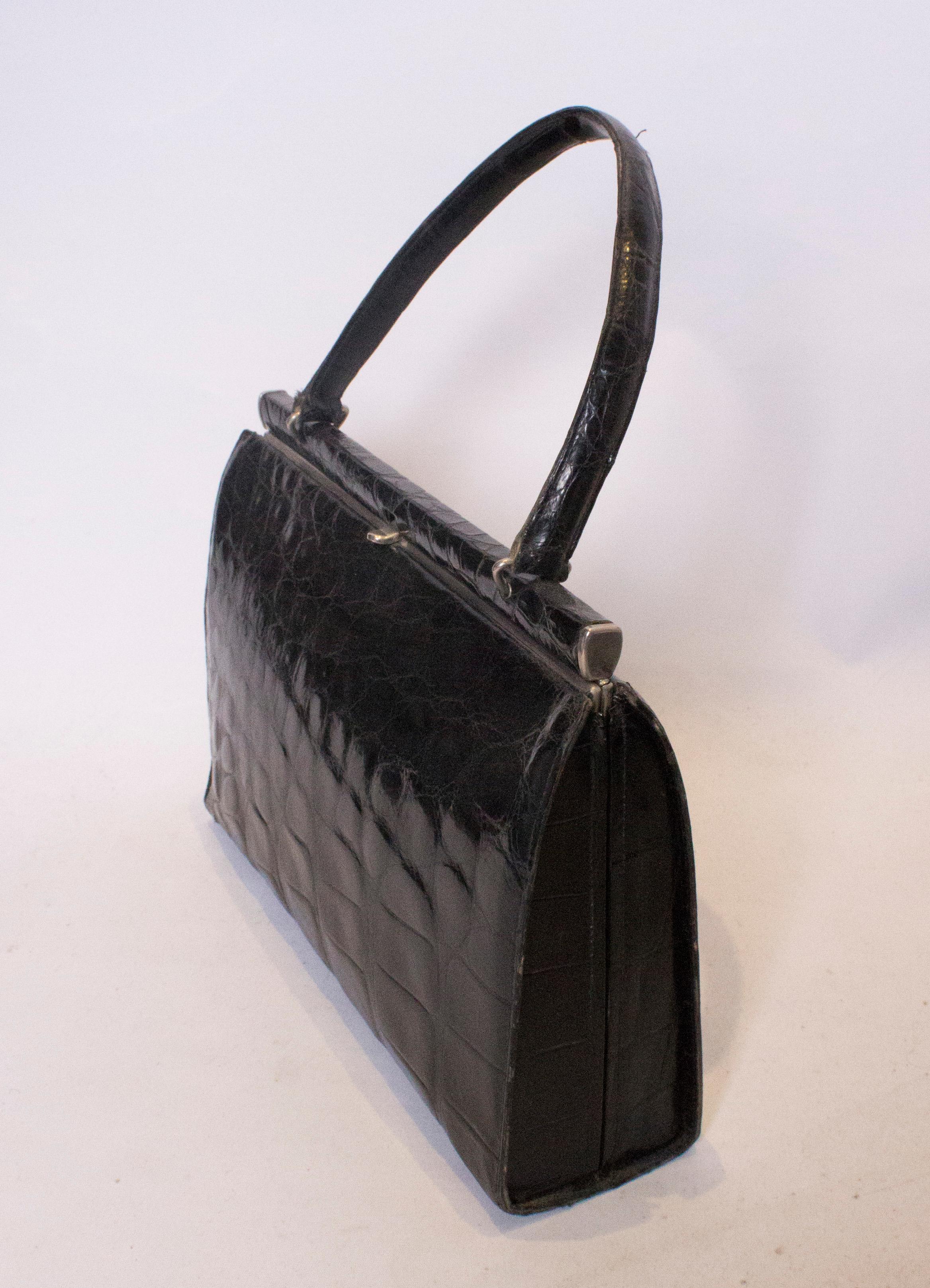 Eine schicke Handtasche aus Krokodil im Vintage-Stil,  Die Tasche hat einen zentralen Verschluss oben und innen gibt es eine Beuteltasche und eine Reißverschlusstasche.
Maße: Breite 12'', Höhe 8 1/2'', Tiefe 3 1/4''.