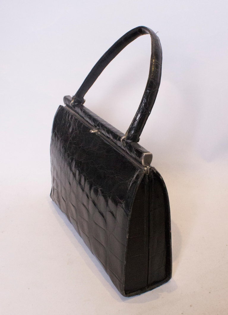 A chic vintage crocodile hand bag,  The bag has a central top fastening and internally there is one pouch pocket and one zip pocket.
Measuerments: width 12'', height 8 1/2'', depth 3 1/4''.