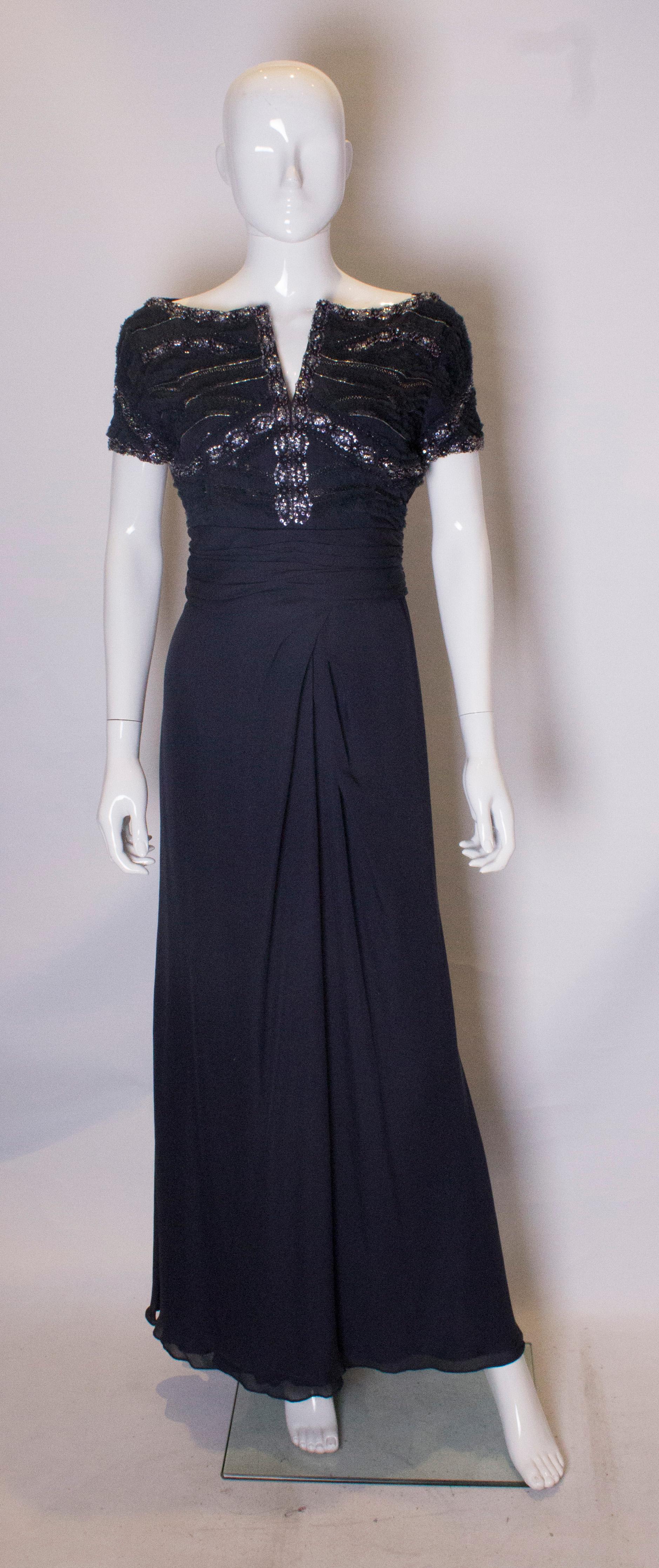 A stunning evening gown by Tomasz Starzewski Couture. The dress is in a deep blue silk with  sequin and fabric detail over the bust area and cap sleaves. The skirt is two layers of silk and the dress is fully lined with a central back zip. There is