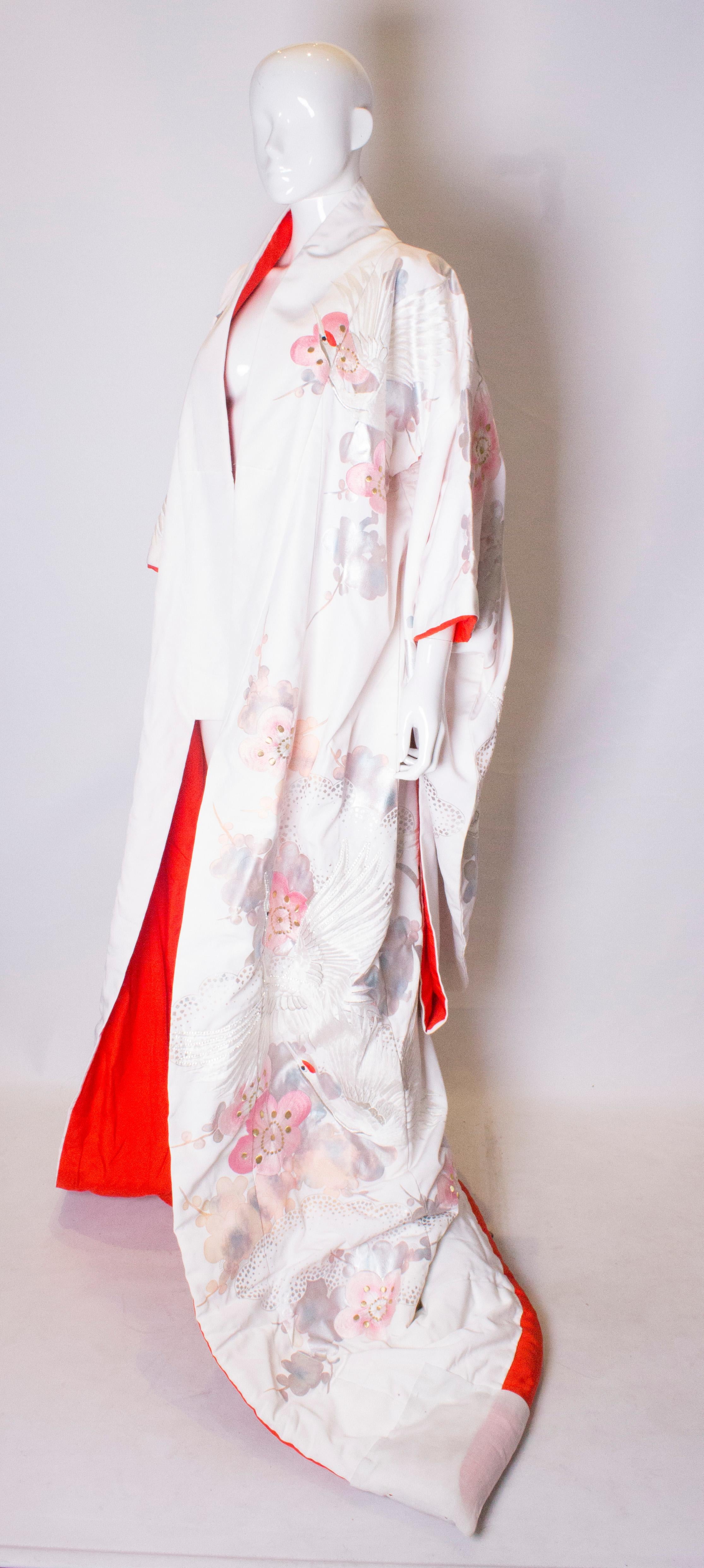 A stunning vintage wedding kimono. The kimono has a white /ivory background, and is heavily embroidered with cranes,  and flowers in shades of pink, silver and gold.  It has a red lining and a padded hem.
Measurements , bust up to 44'', length 77''.