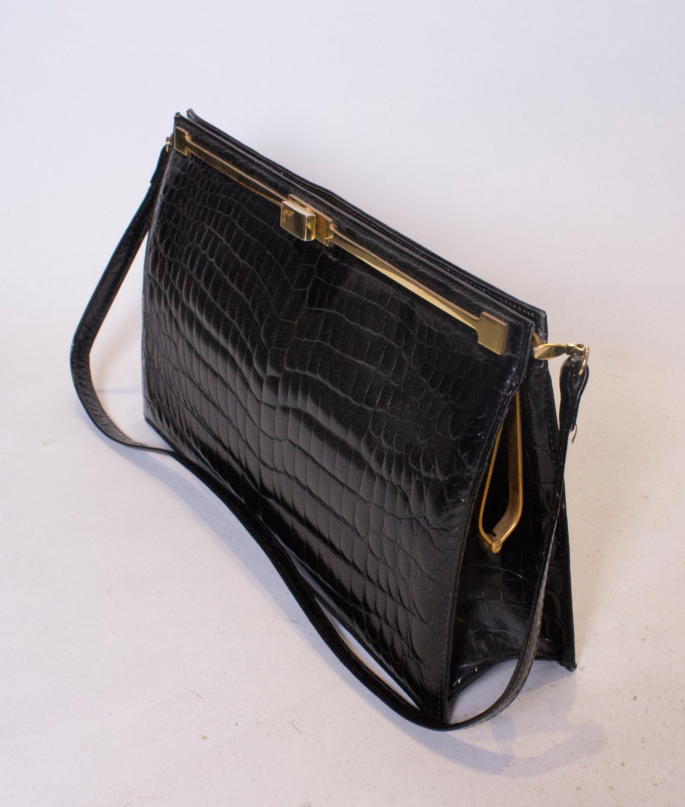 A chic vintage crocodile bag by Bon Gout . This super shiny crocodile bag is large enough for todays essentials, measuring  Width 13'', height 7 1/2 '', and depth 3''. The bag has a long shoulder strap and an internal zip pocket.