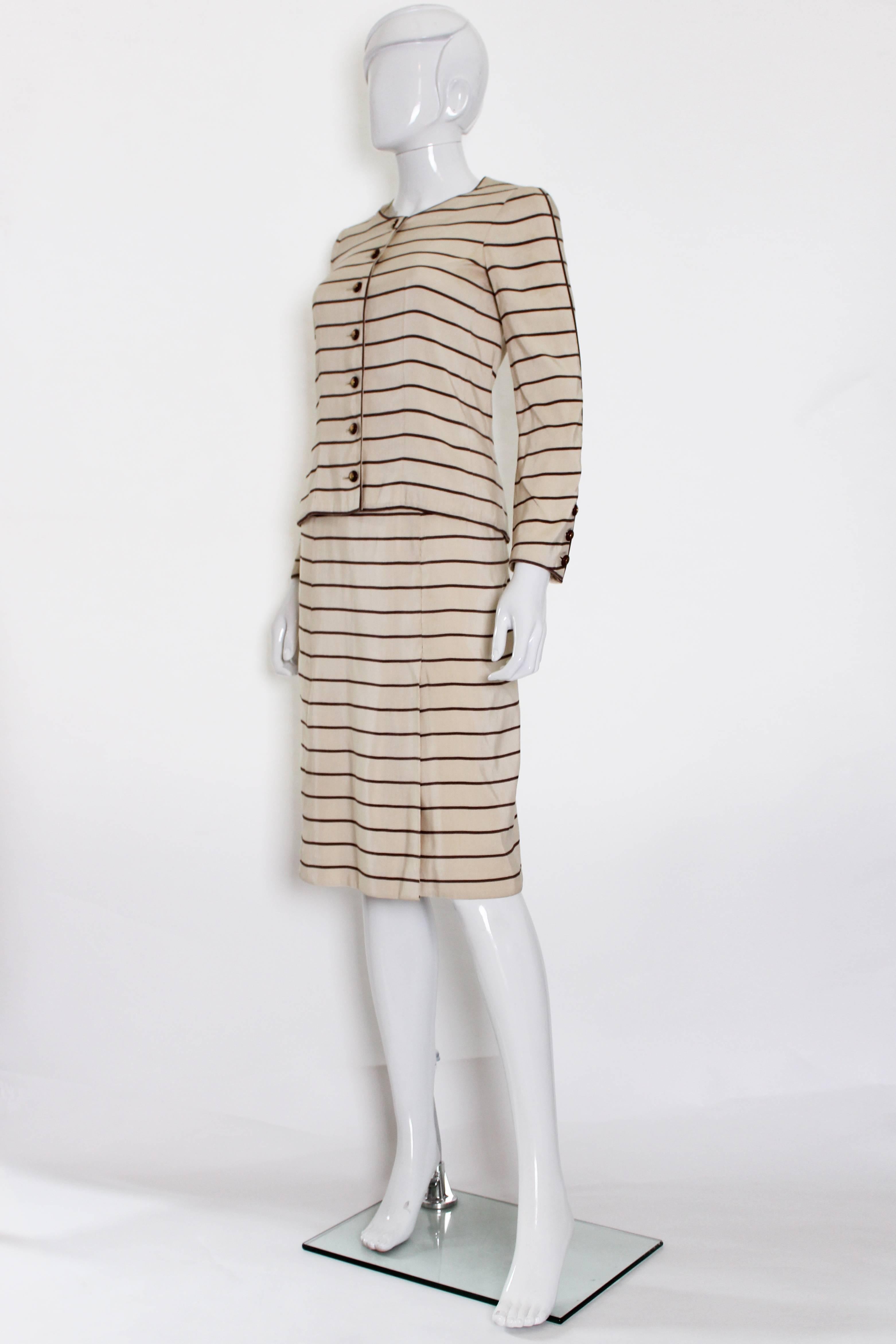 A charming and chic haute couture skirt suit by Chanel.
The suit is made of a cotton/silk mix, taupe stripes on an ivory background.
The suit is lined in silk , the buttons are made of wood, and the jacket has a chain in the hem. The jacket has a