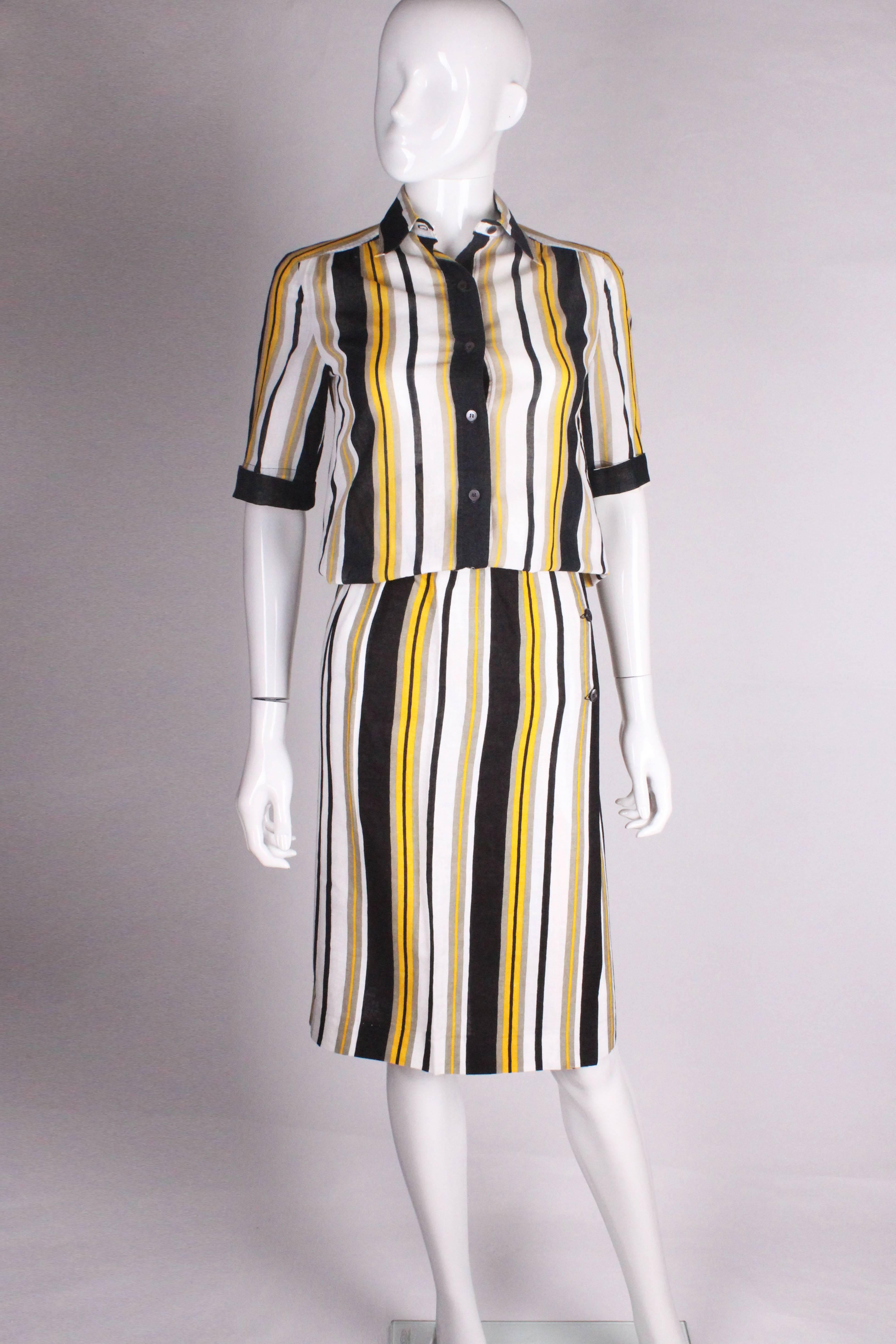 A chic skirt and shirt by Celine. This outfit is 100% cotton, with stripes of white, black, yellow and grey.The shirt has a shirt collar, button front and short sleeves with turn up cuffs . The skirt is a wrap over with three buttons.
Shirt bust