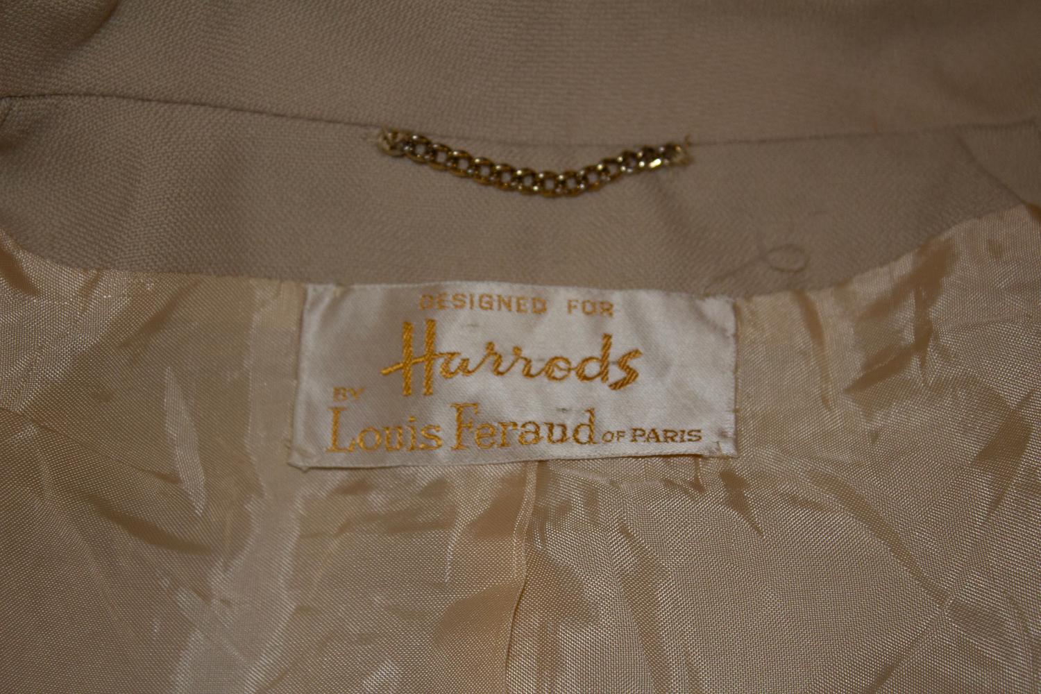 Un elegante tailleur con gonna vintage, progettato  per Harrods da Louis Feraud, Parigi. In lana color biscotto, la giacca è dotata di quattro tasche, di cui due in corrispondenza di  tasche sui fianchi e due tasche sul petto. La giacca è dotata di