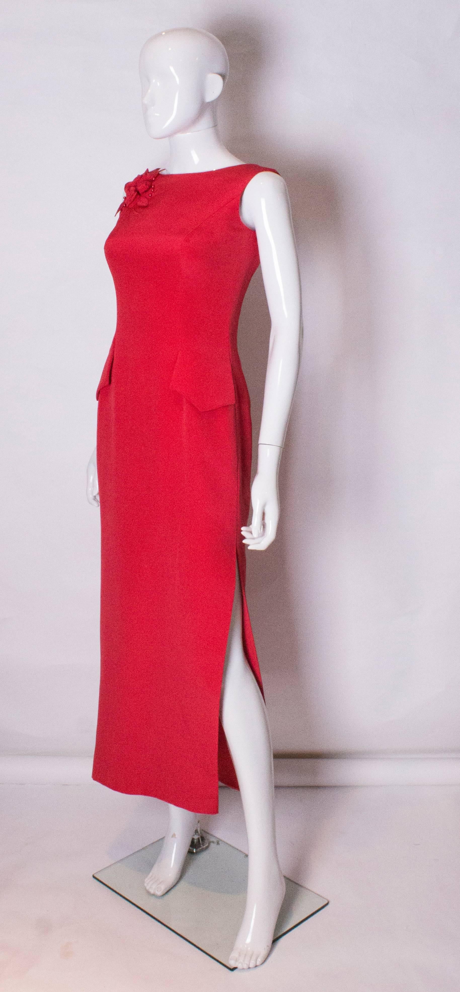A stunning evening gown by British designer Tomasz Starzewski,  The dress has a slash neckline at the front and a deep v neckline at the back with a central back zip.It has a red floral and bead decoration on the right shoulder, a slit on the left