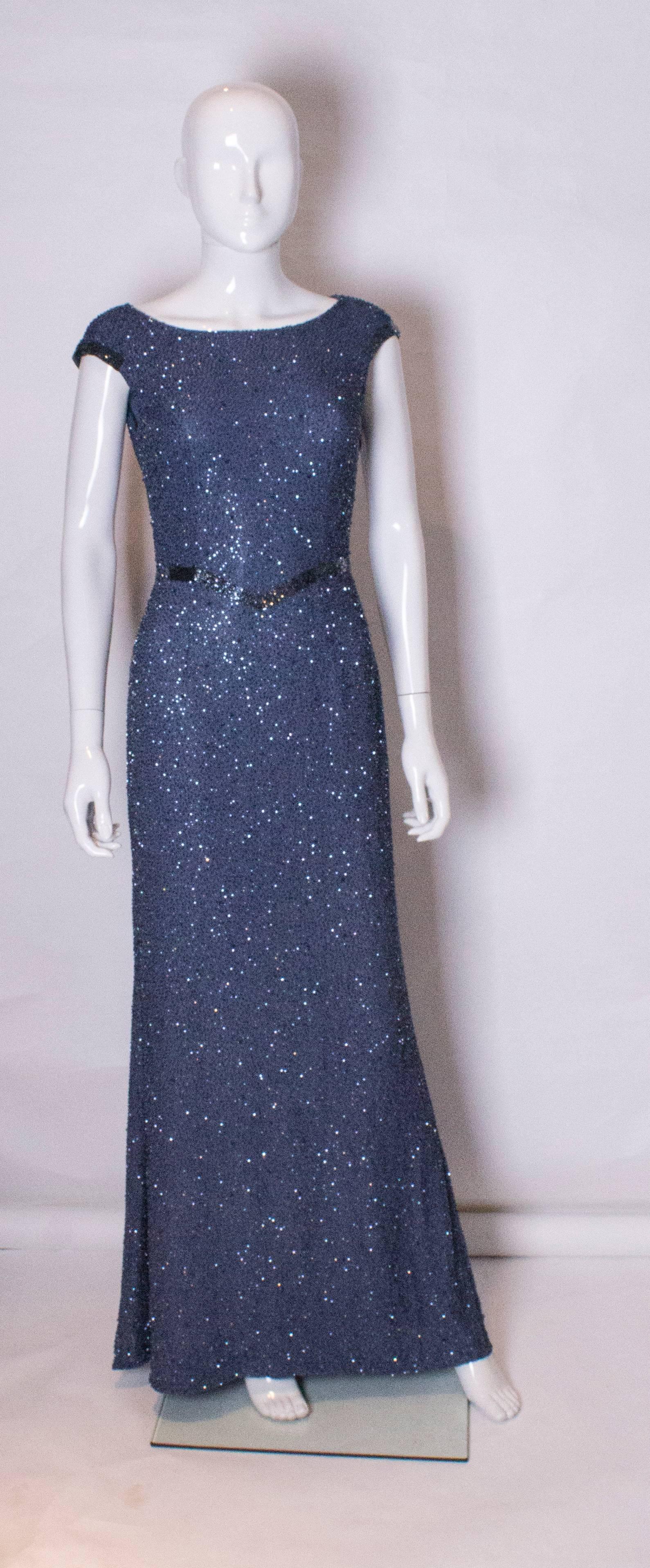 An elegant evening gown by British designer Tomasz Starzewski.The fabric , and lining of the dress are silk, and the dress has a scoop neck at the front and a cowl neck at the back.
There is a contrasting band of beads on the arm holes and at waist