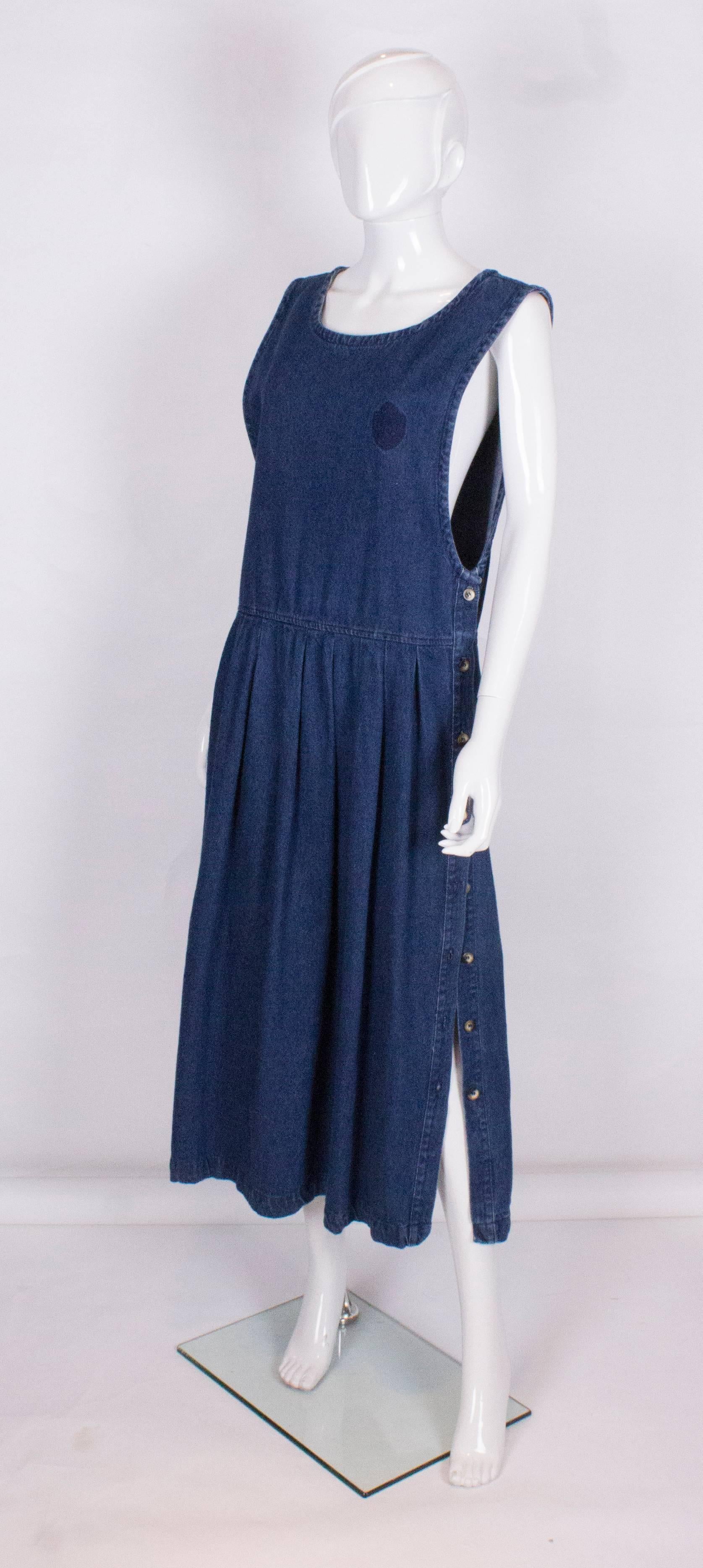 A great work wear dress by Pierre Cardin. In a heavy denim, with a round neck and 8 button opening on each side from the waist down.