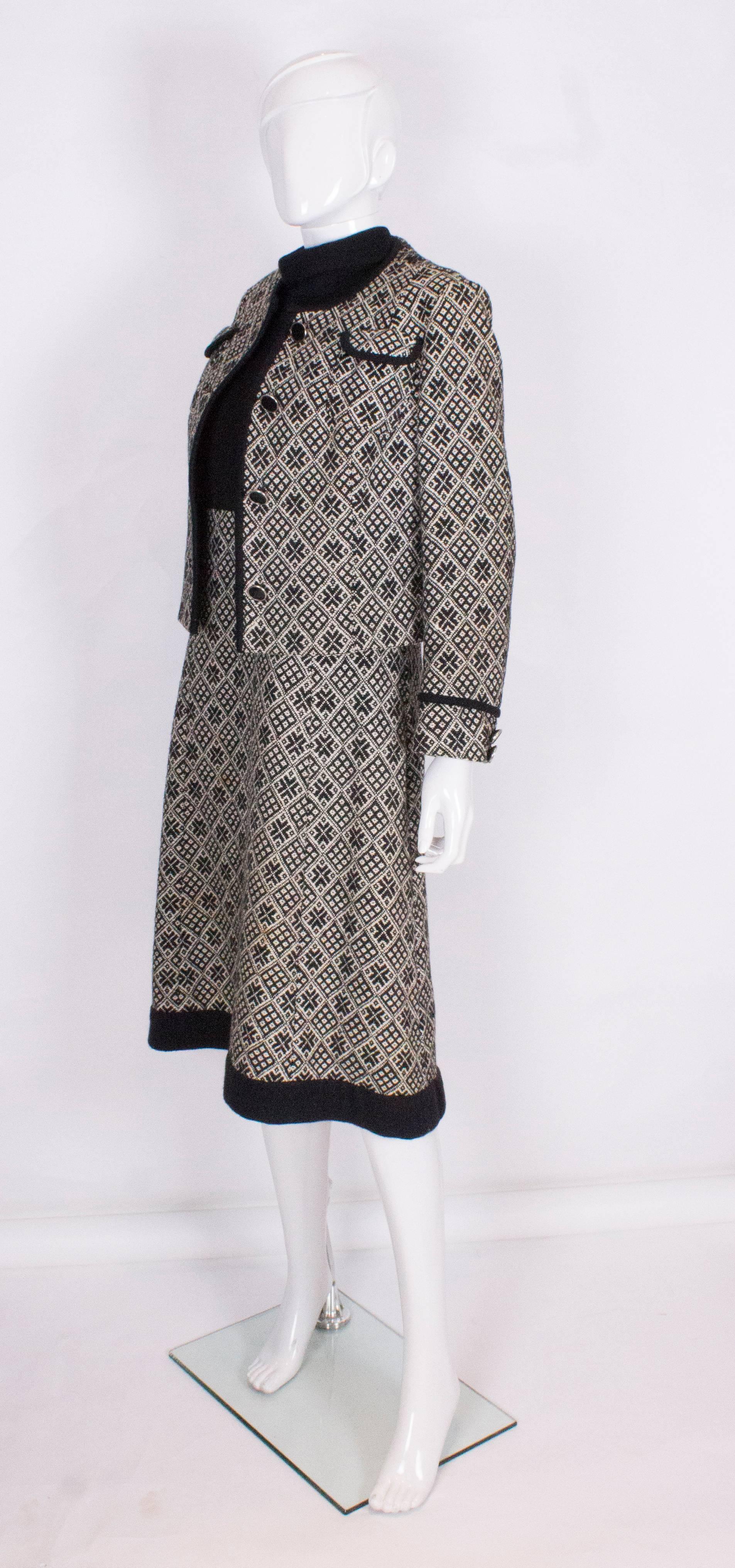 A chic outfit for Fall. The jacket has a four button front opening and there are 2 breast pockets and 2 buttons on each cuff. The dress has a roll neck, black body and trim at the hem. The body of the dress is the same black and white woven fabric