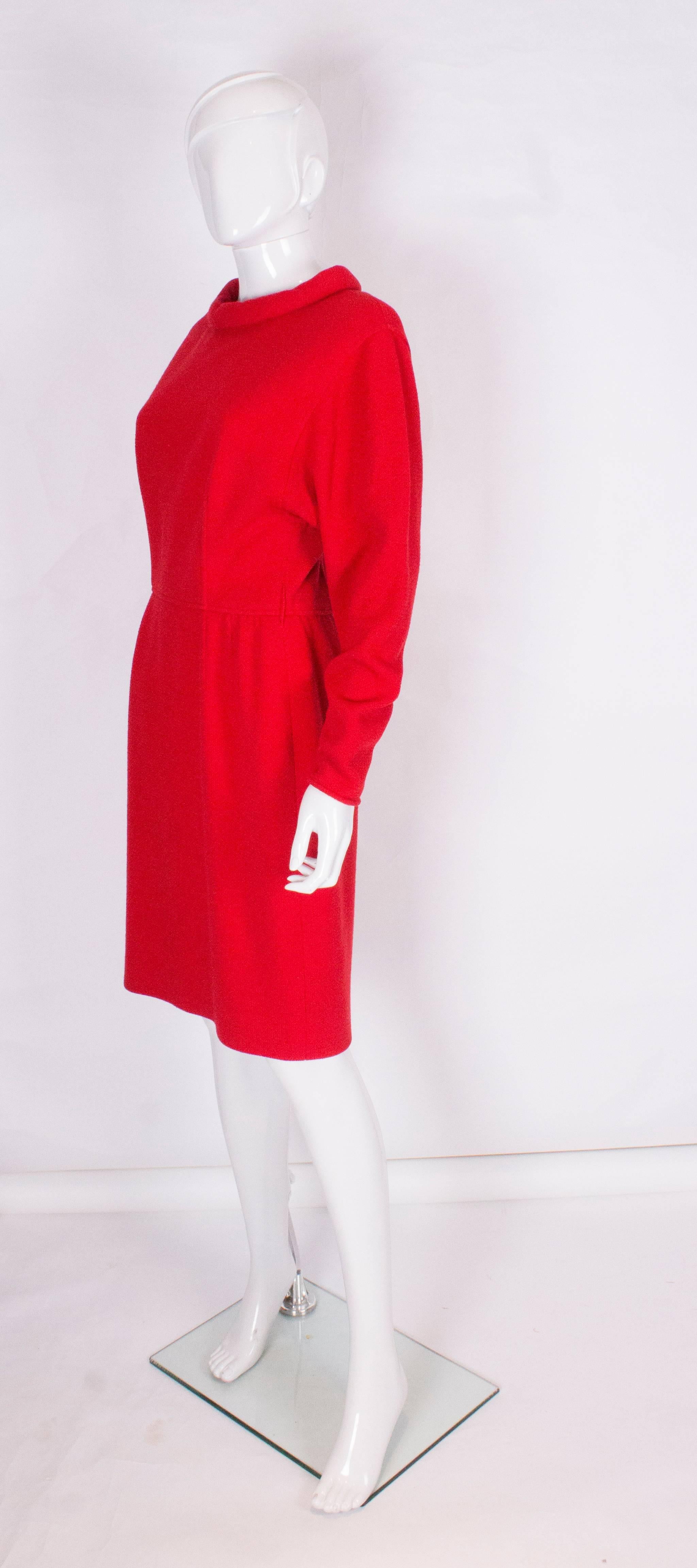 A chic red dress by Valentino. The dress has a low round neck line, with a 6 button back opening to the waist, and a zip opening from the waist down.There are 3 1/2'' zip openings on each sleeve.The dress is fully lined.