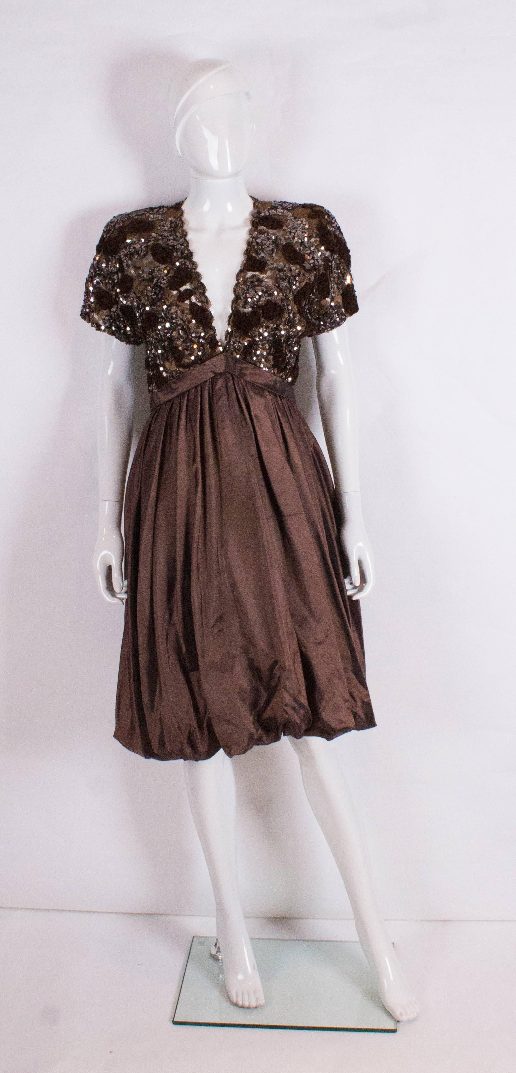 A great evening dress by Gicol. The dress has a brown sequin and lace upper body and silk skirt. It has a v neckline, ,cap sleeves ,central back zip and elastic at the back of the bubble hem enabling you to walk more easily. In addition there is a