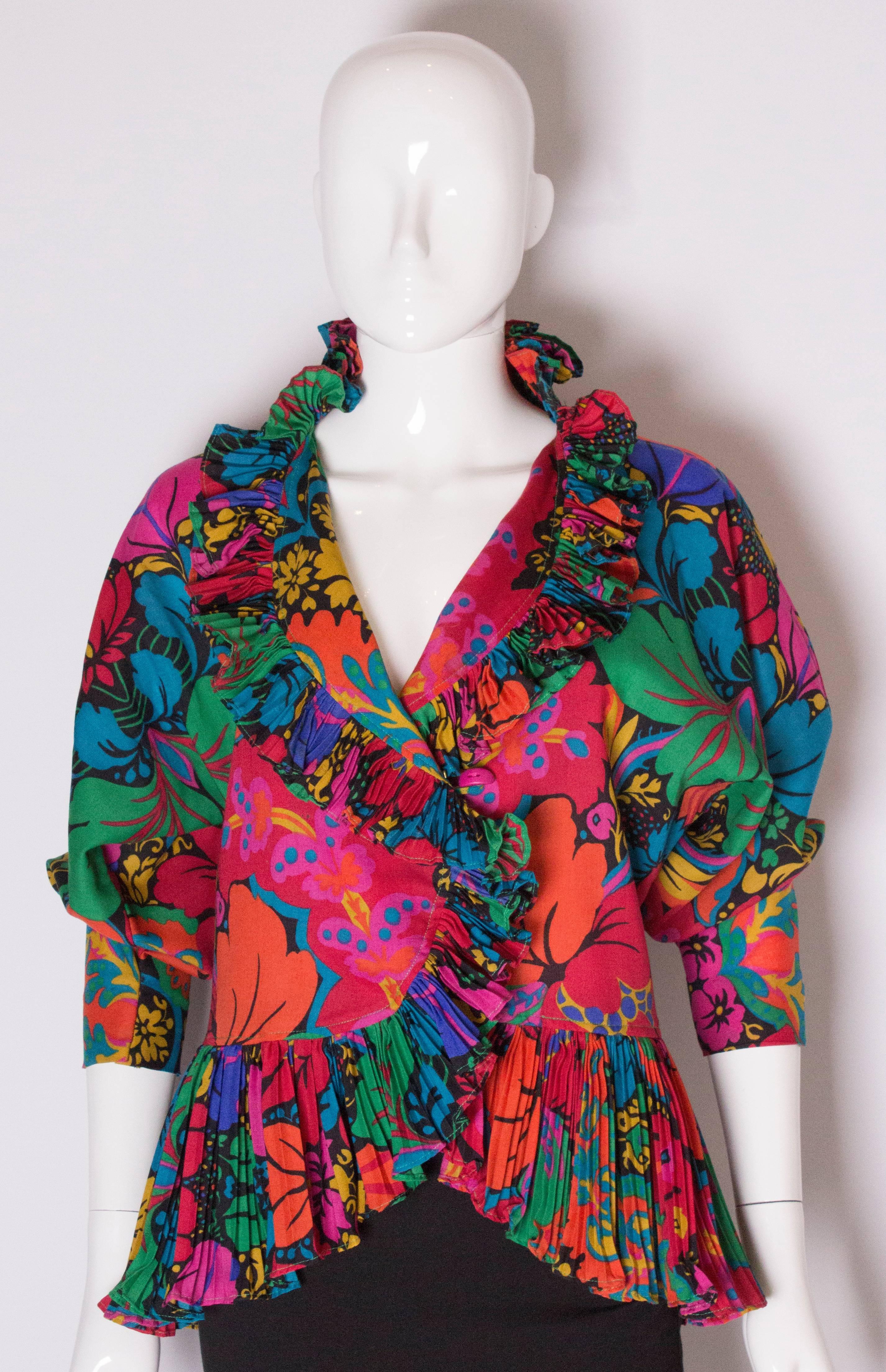 A great jacket/top by Jean Muir. In a vibrant wool print, the jacket has frill at the hem and collar, and a wrap over front with two buttons.