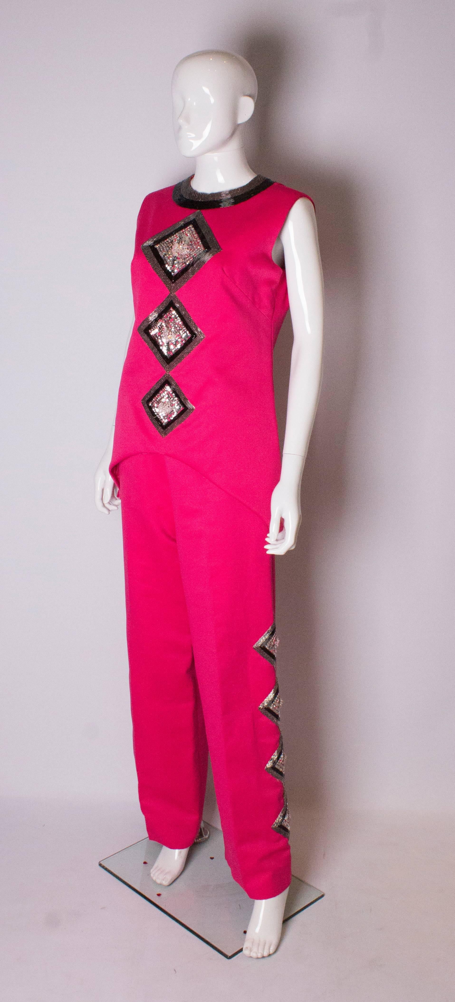 A chic pink pantsuit by Valentina, number RN34438. The top has a round neckline with beading , is sleevless and has a 10'' slit on either side. It had wonderful bead and sequin decoration on the front , is fully lined and has a central back zip.
The