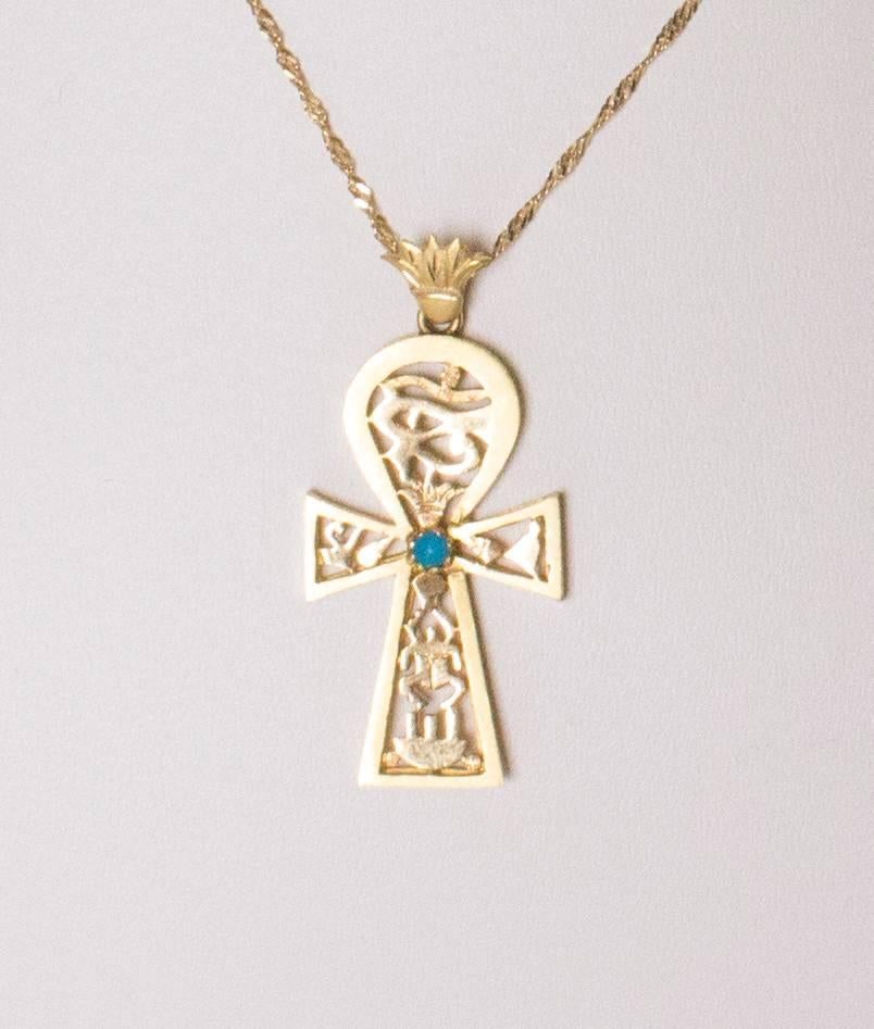 A gold link chain measuring 16'', with a gold cross measuring 1 1/2'' by 3/4'', and has turquoise stone in the centre.