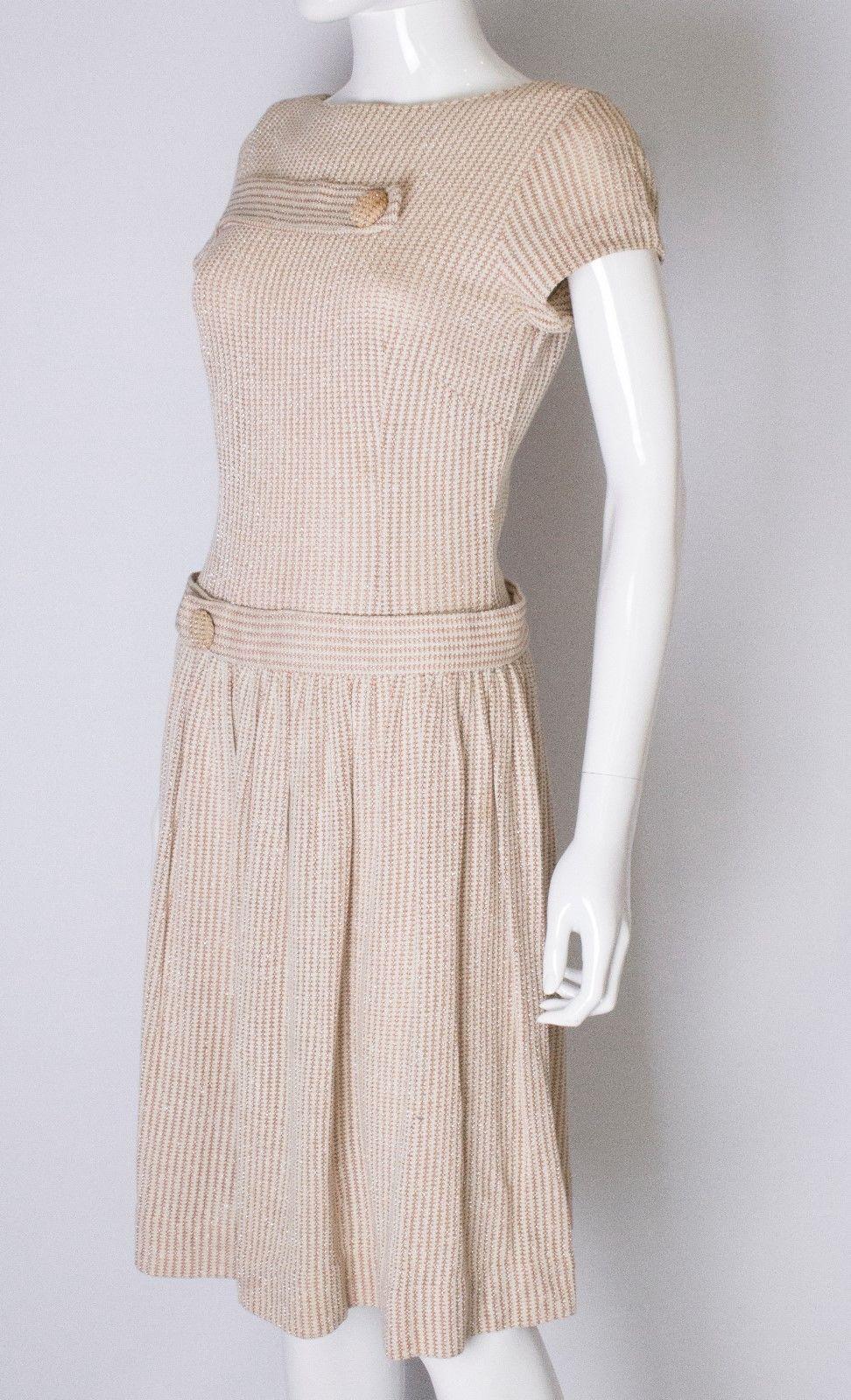 A vintage 1950s cream woven dress with red and silver thread throughout 

drop waist with two large button detail zips at the back

measurements taken flat in inches 

bust -17
waist -15
length - 42
 
uk 8 - 10