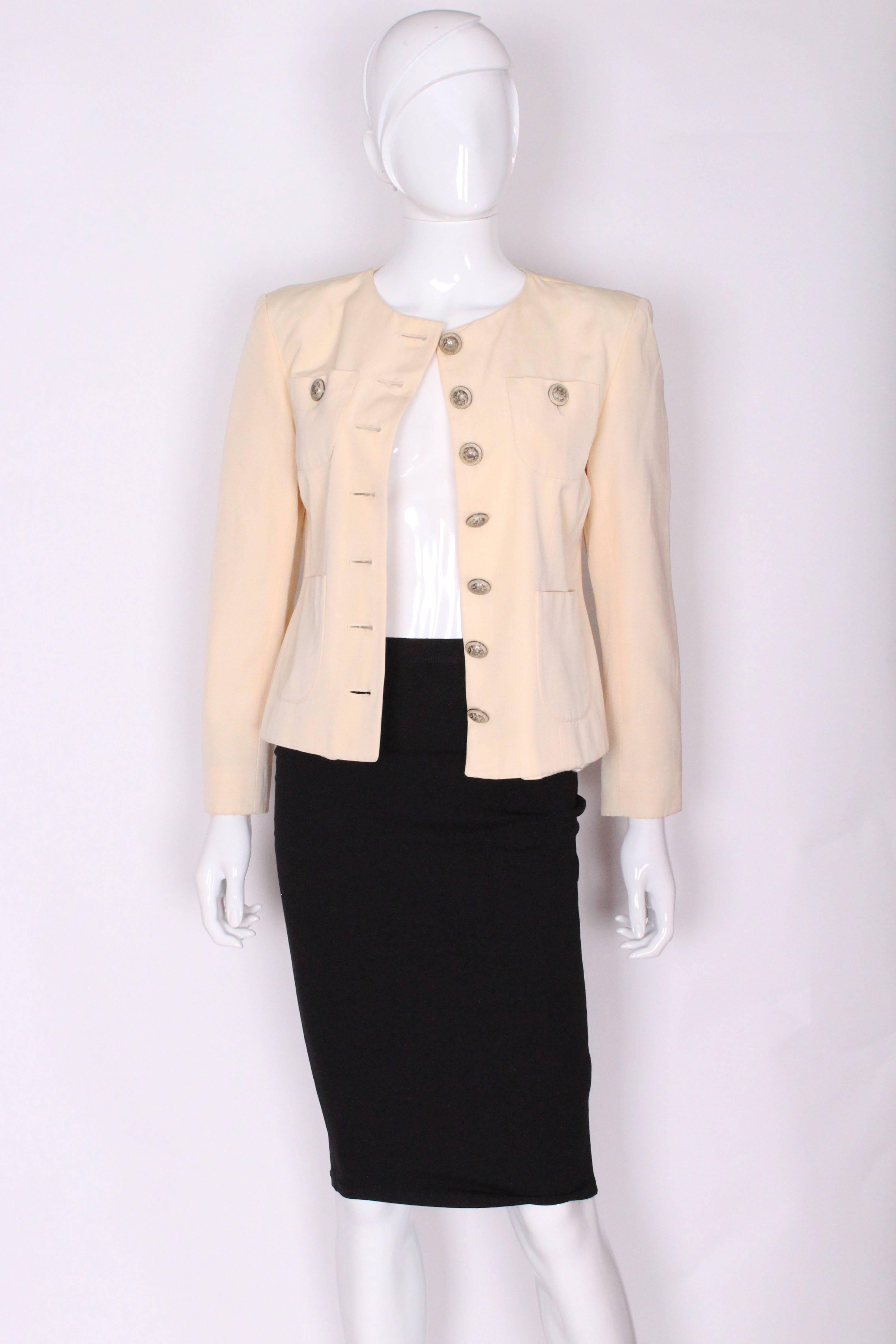 A chic cream jacket by Yves Saint Laurent , Encore line.
This jacket is made of a clotted cream colour fabric with a fine rib detail. It is collarless, with 4 pockets on the front. It has a central 7 button opening with a button on each breast