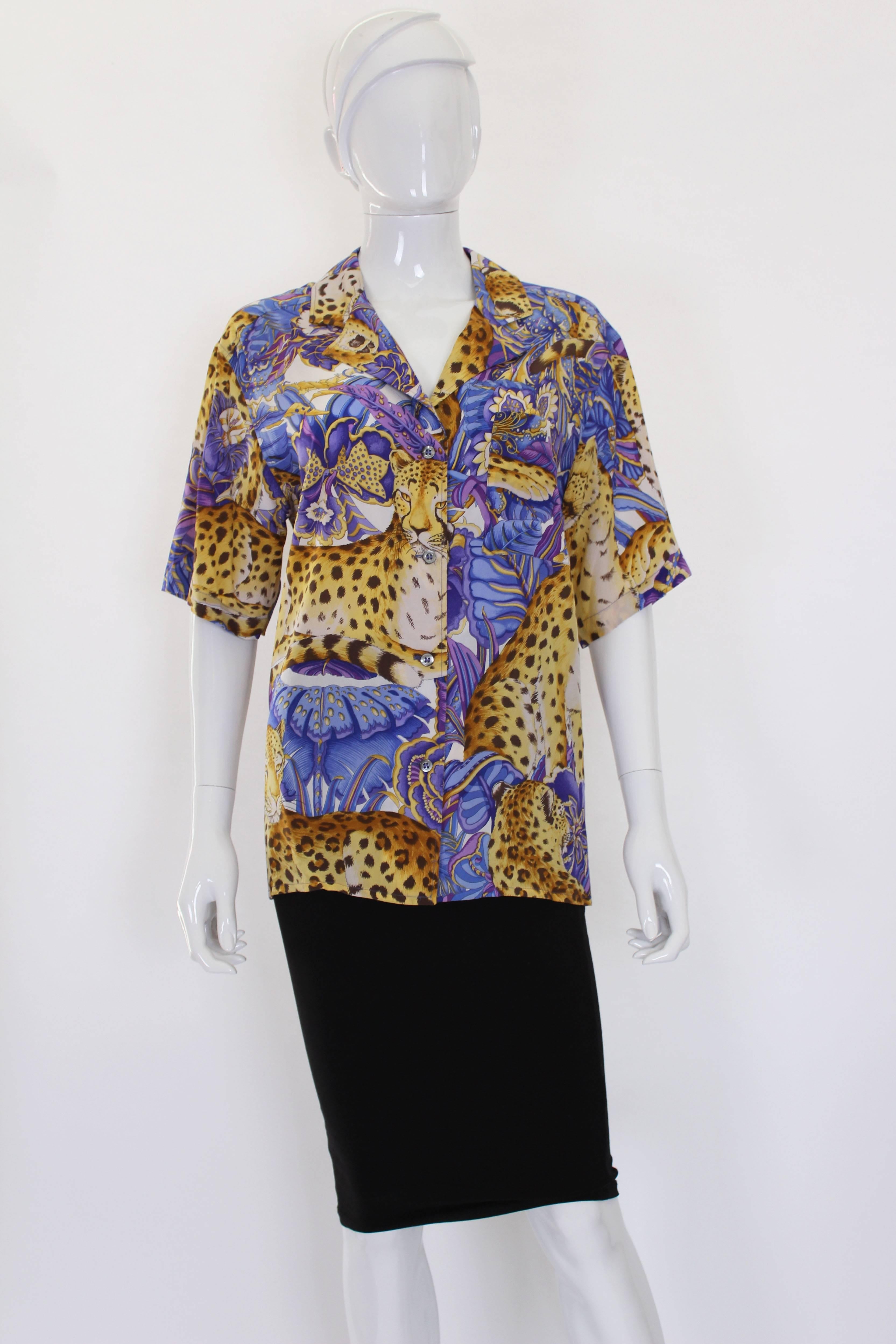 A wonderful silk shirt by Italian house Salvatore Ferragamo. This shirt  has a colourful print of leopards and flowers, in gold, brown, purple, mauve and white. It has a 4 button opening at the front, a breast pocket on the left hand side and short