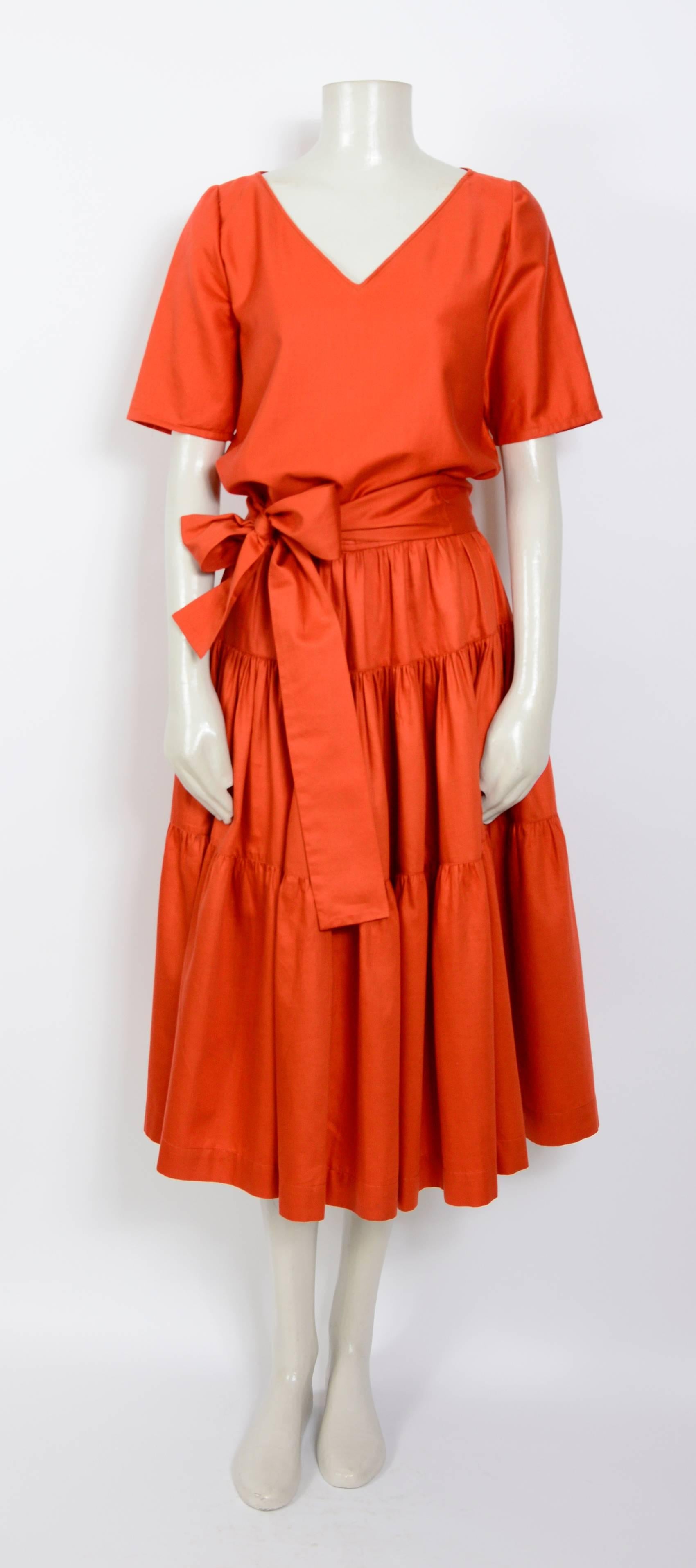 A fabulous 1960's top and skirt from YSL Rive Gauche in Redstone red polished cotton. The skirt has a fitted waistband, 3 gathered panels each widening towards the hem making it fuller and a wide tie belt. The top slips on over the head and the