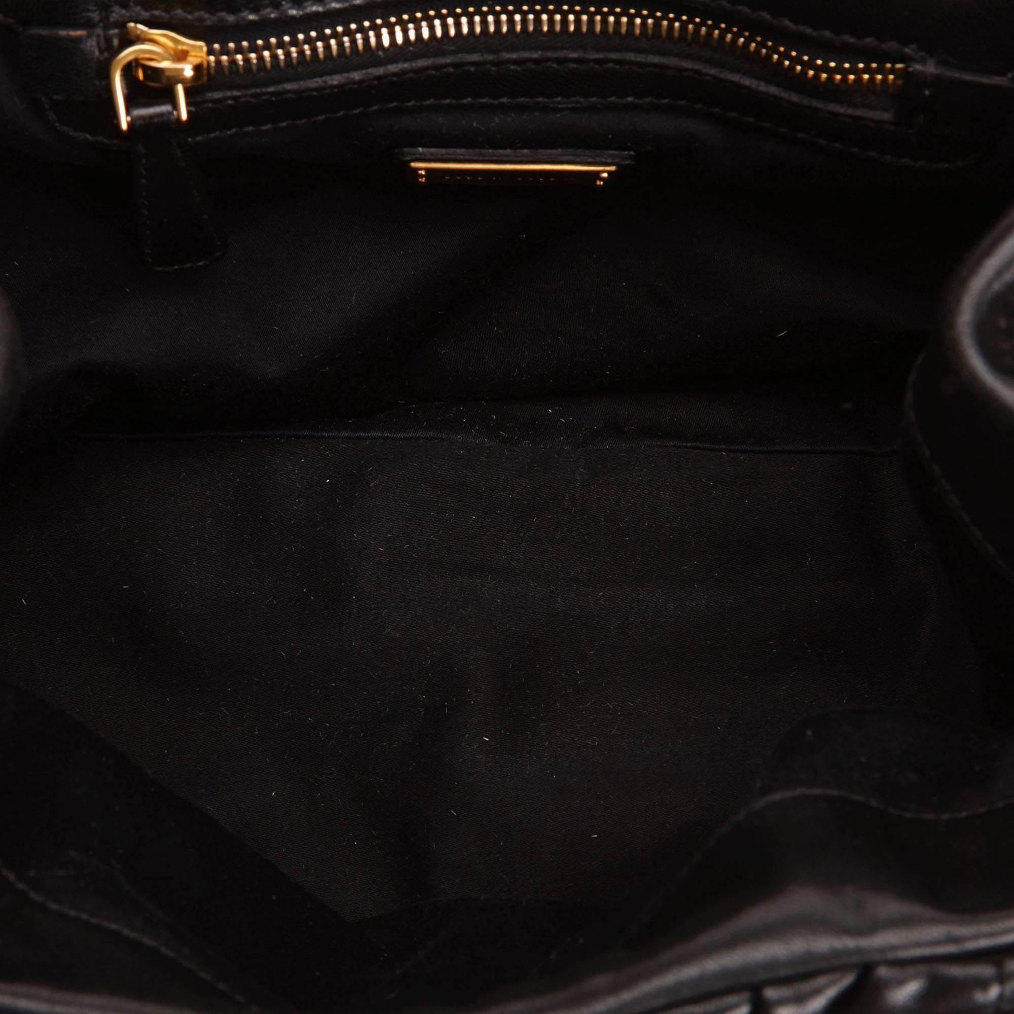 The Coffer features a gathered leather body, braided straps, gold-tone hardware, a front strap with a push lock closure, and interior zip and slip pockets.

Color: Black