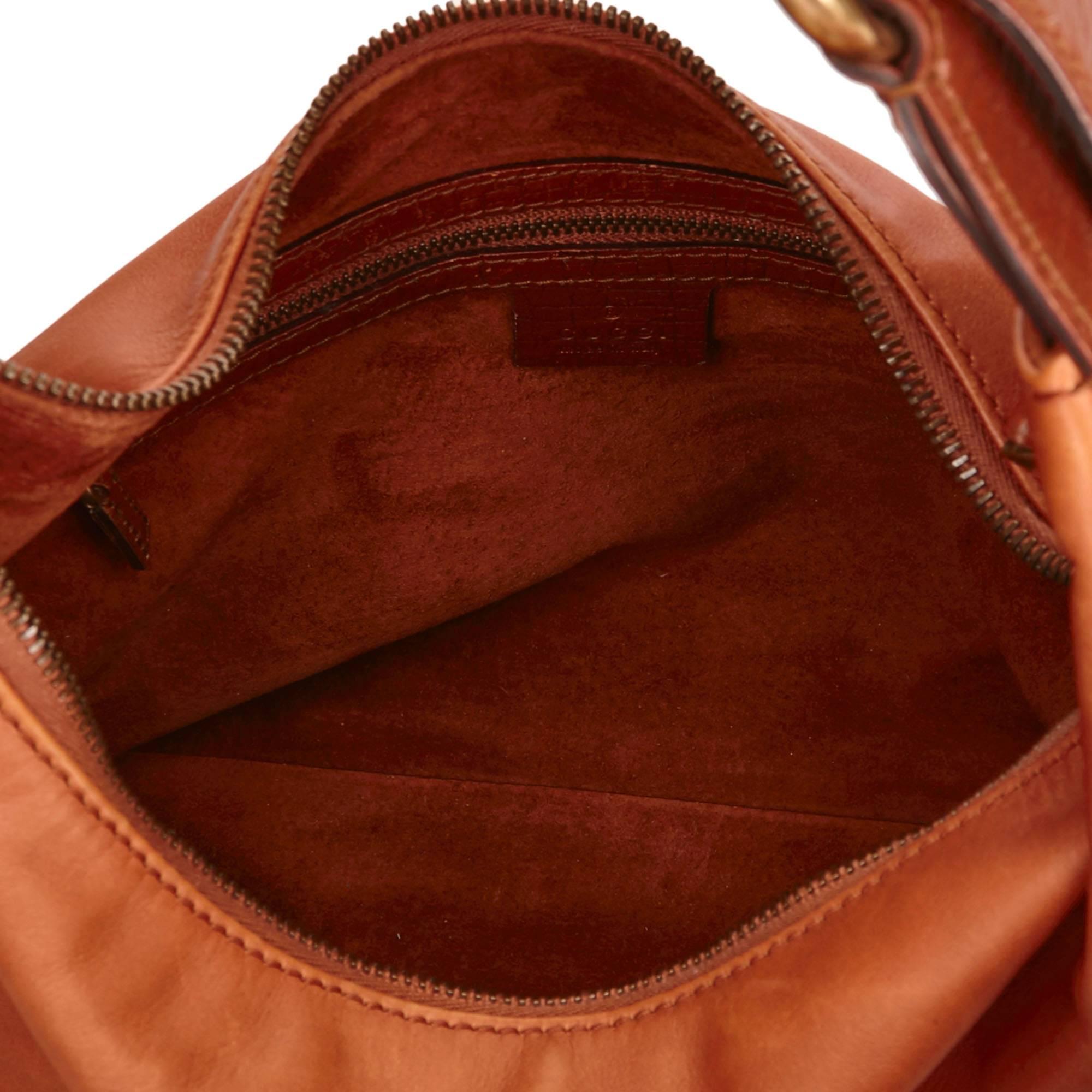 This shoulder bag features a coated canvas body, a flat shoulder strap with horse bit details, a top zip closure, and an interior zip pocket.

Color: Brown