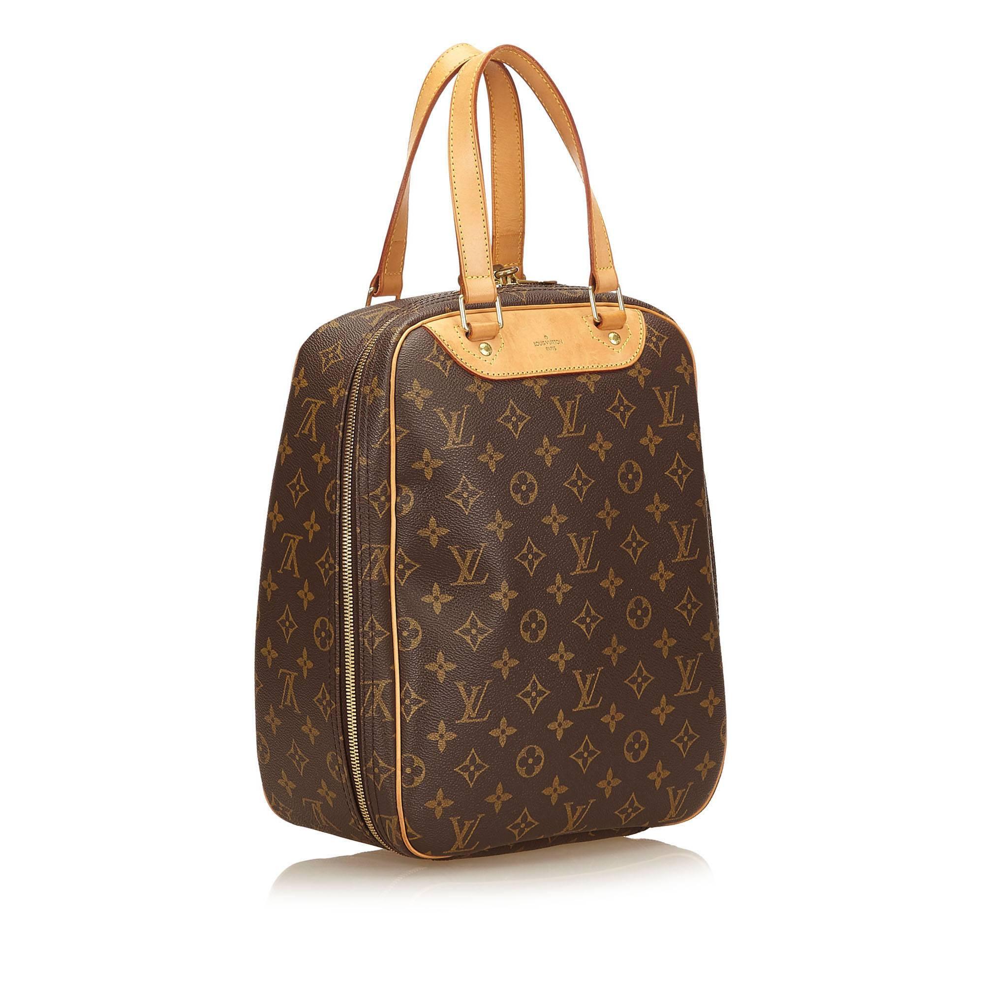 The Excursion features the Monogram canvas, rolled vachetta handles, vachetta trim, a zip around closure, and an interior flat pocket. 

It carries a B condition rating.  

Dimensions: 
Length 24 cm
Width 32 cm
Depth 15 cm
Hand Drop 14