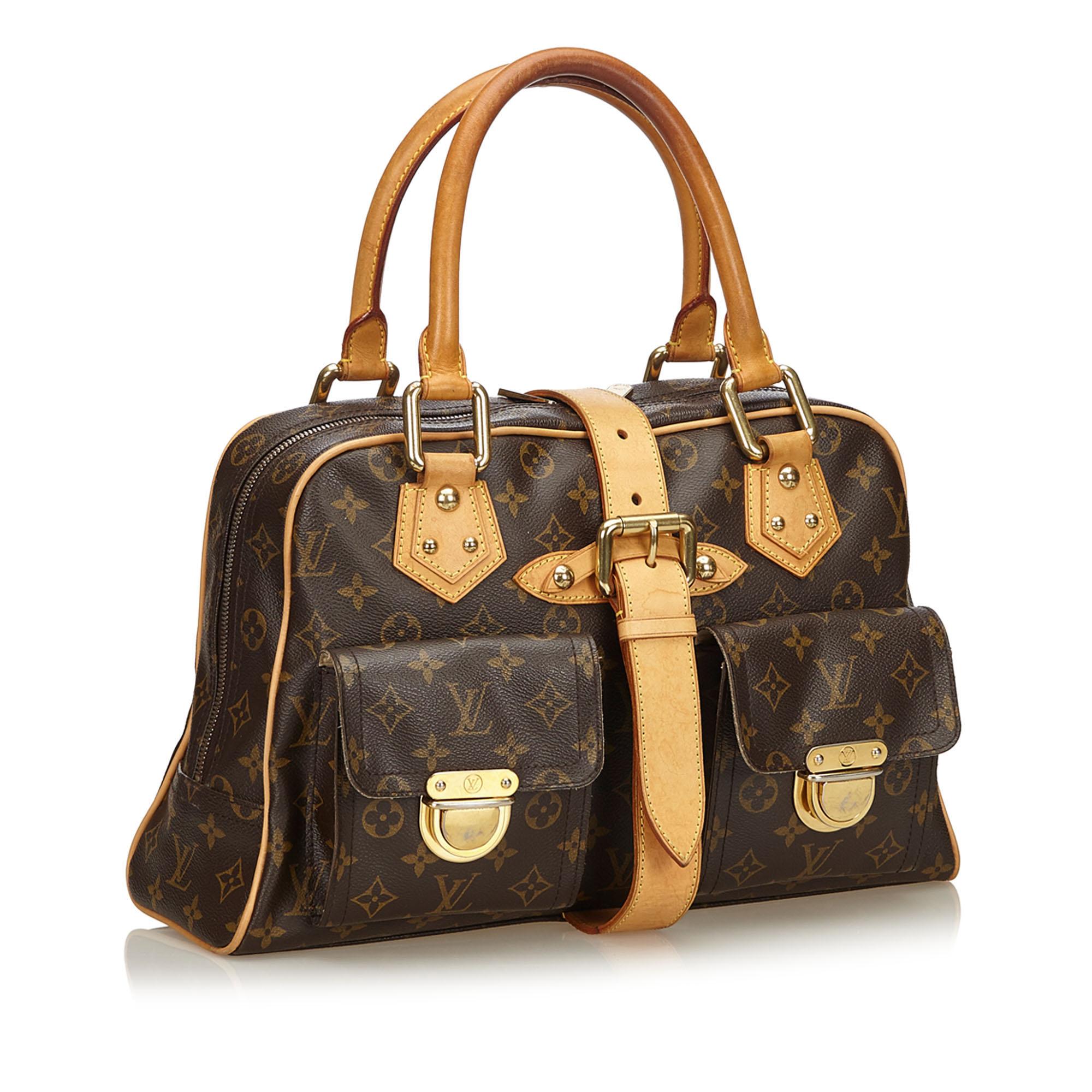 The Manhattan GM features a monogram canvas body, rolled leather handles, exterior flap pockets with gold-tone hardware and push lock closures, a top strap with a belt buckle detail, a top zip closure, and an interior slip pocket.

It carries a B