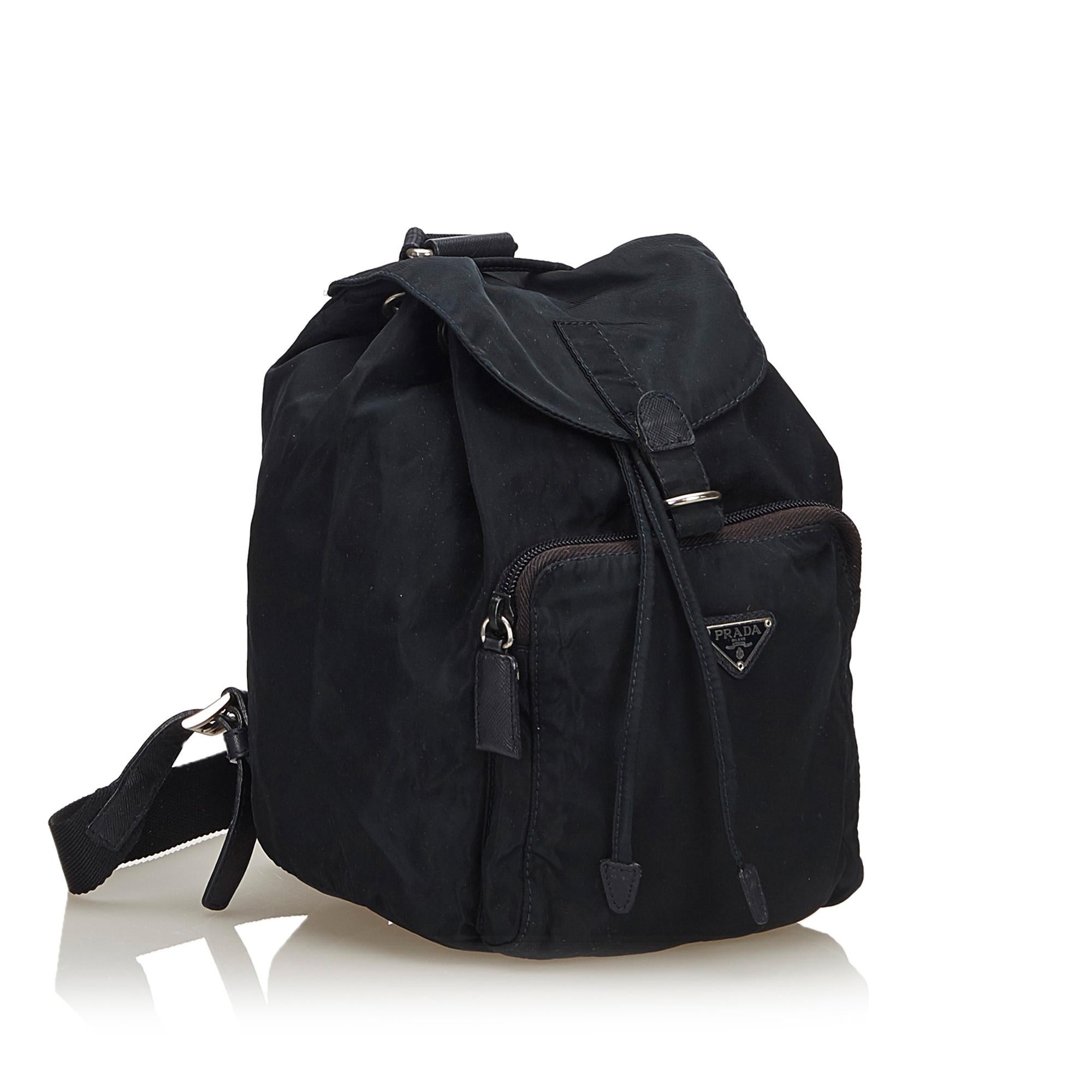 This backpack features a nylon body, flat back straps, top flap with buckle closure, drawstring closure, an exterior zip pocket, and interior zip pocket.

It carries a B condition rating.

Dimensions: 
Length 25 cm
Width 18 cm
Depth 13 cm
Shoulder