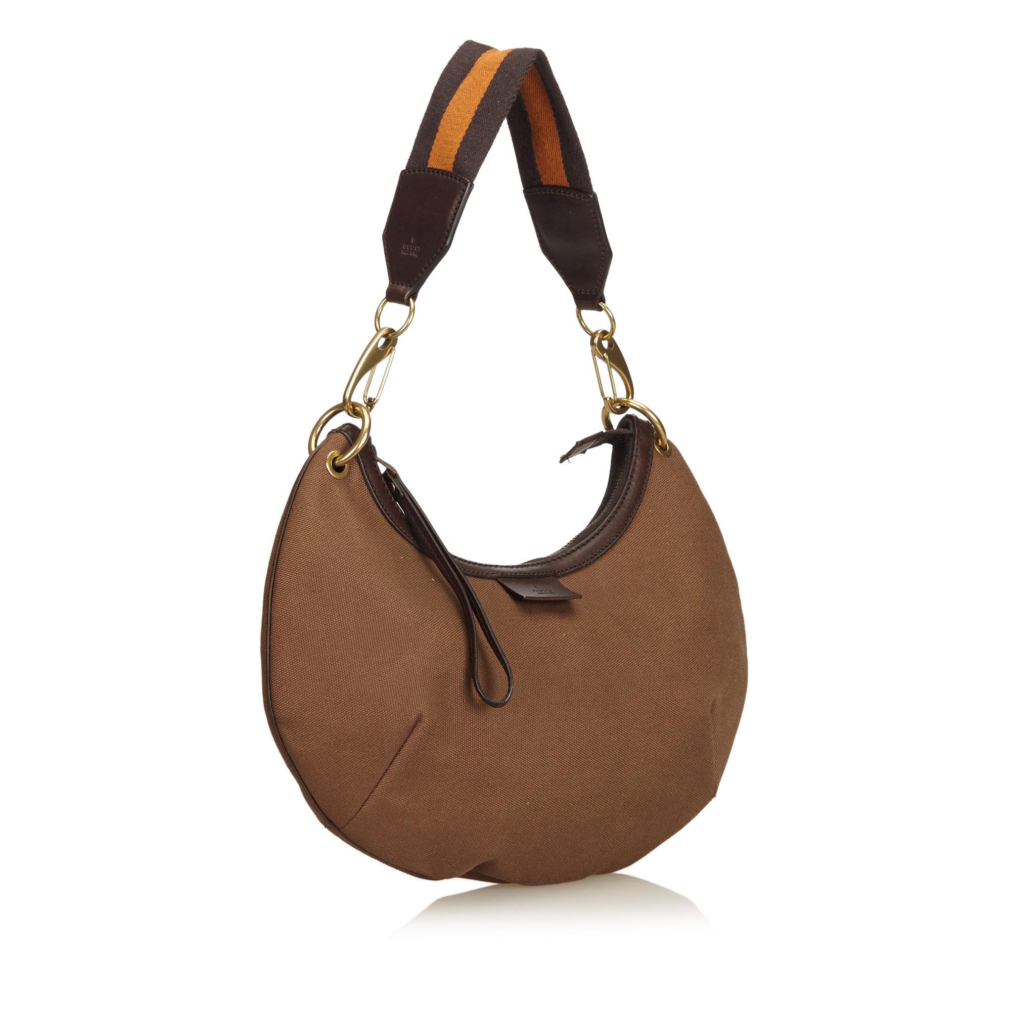 This shoulder bag features a canvas body with leather trim, flat strap, top zip closure and interior zip pocket.

It carries a AB condition rating.

Dimensions: 
Length 21.00 cm
Width 33.00 cm
Depth 2.00 cm
Shoulder Drop 25.00 cm

Inclusions: Dust