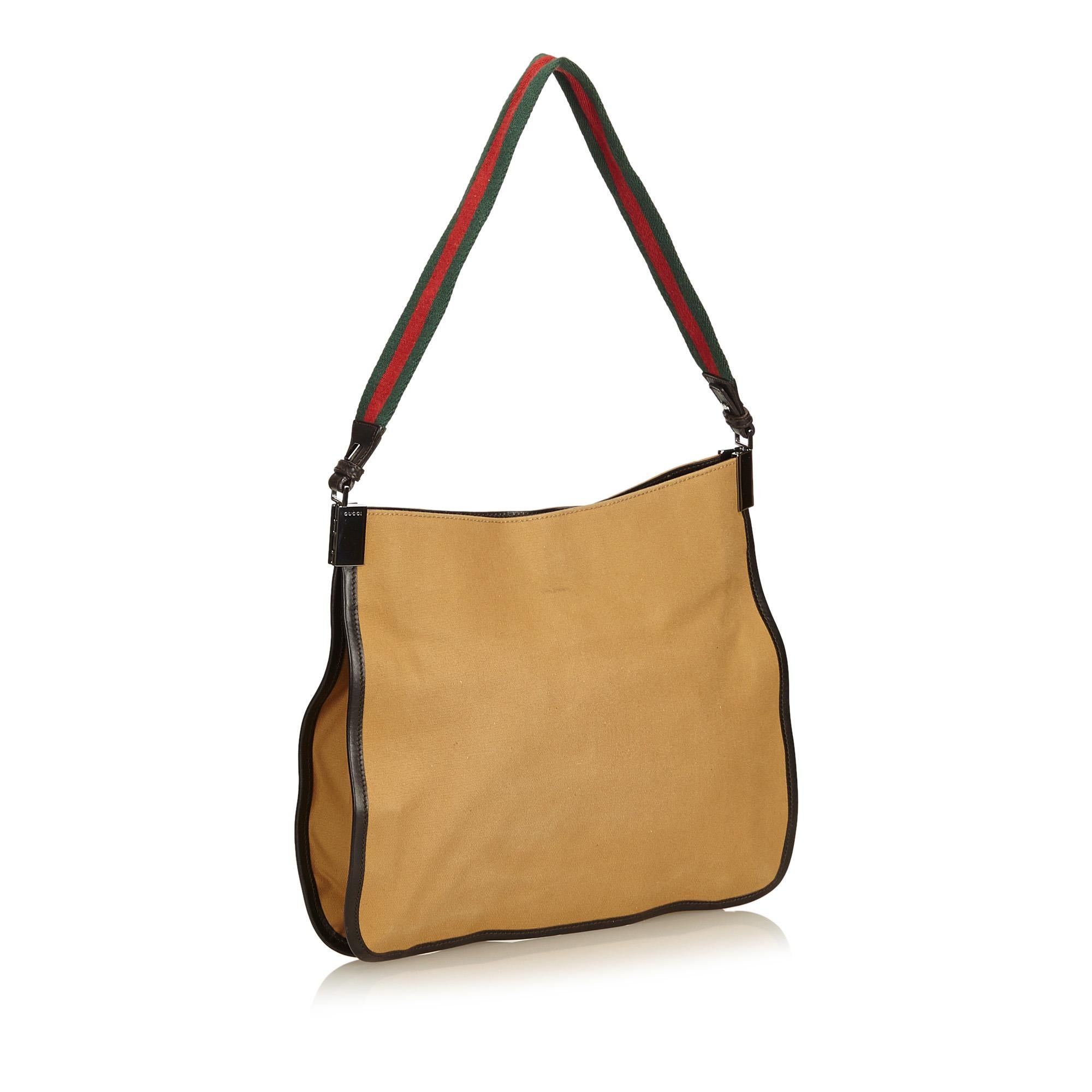 This shoulder bag features a canvas body, flat strap, open top with magnetic snap closure, and an interior zip pocket.

It carries a AB condition rating.

Dimensions: 
Length 26.00 cm
Width 31.00 cm
Depth 5.00 cm
Shoulder Drop 25.00 cm

Inclusions: