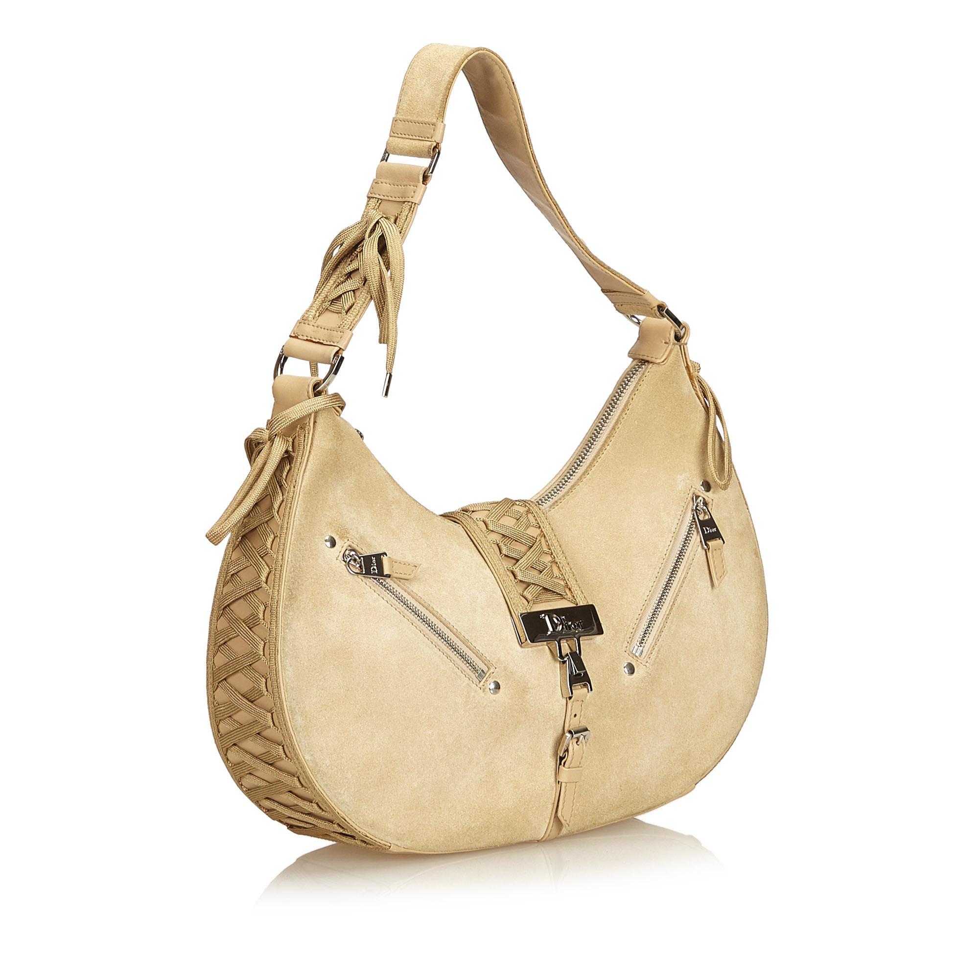 The Admit It Shoulder Bag features a canvas body, leather trim, a flat adjustable shoulder strap with a lace up detail, a front flap with a lace up detail and a magnetic closure, two exterior zip pockets, three interior open compartments, canvas