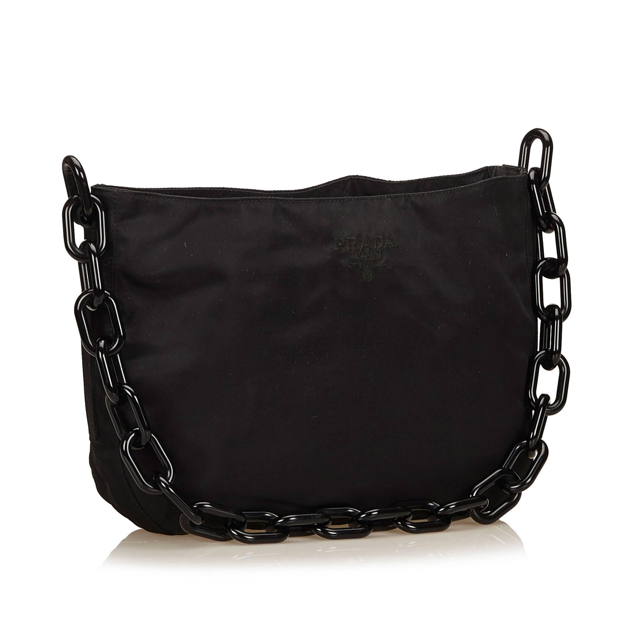 This shoulder bag features a nylon body, resin shoulder chain, open top, and interior zip pocket. It carries a B condition rating.

Inclusions: 
Dust Bag