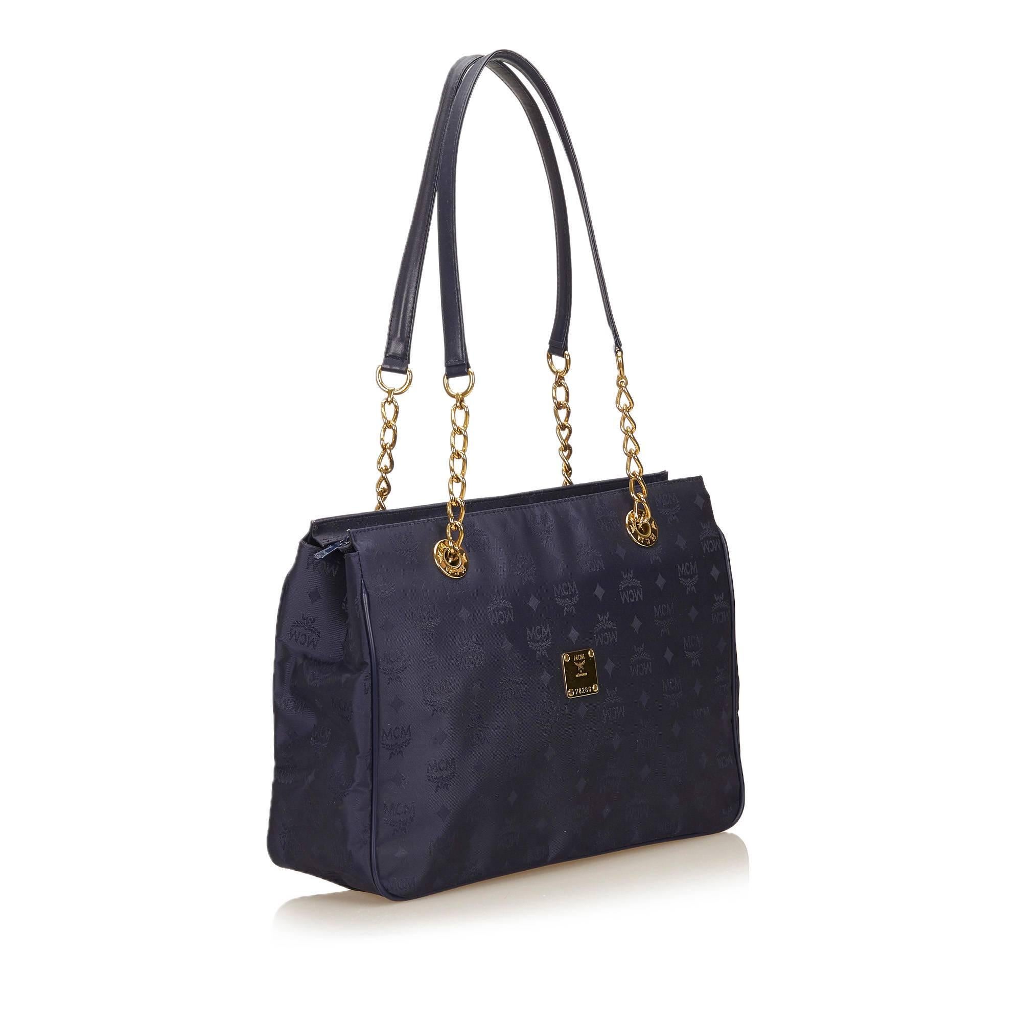 This shoulder bag features a nylon body, flat lether straps with gold-tone chains, a top zip closure, and interior slip pockets. It carries a AB condition rating.

Inclusions: 
None