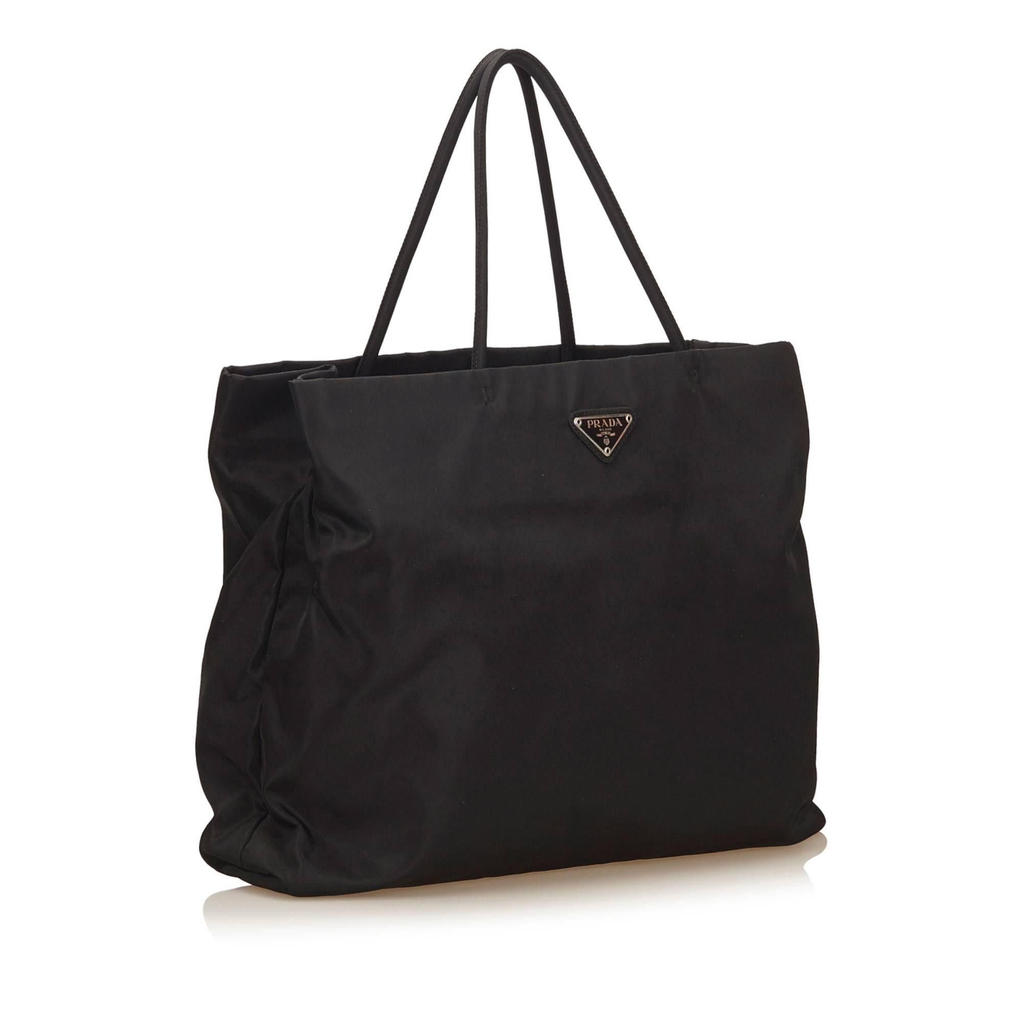 This tote bag features a nylon body, rolled straps, open top, interior compartment, and interior zip pocket.  The bottom is moderately stained sue to transfer of color.