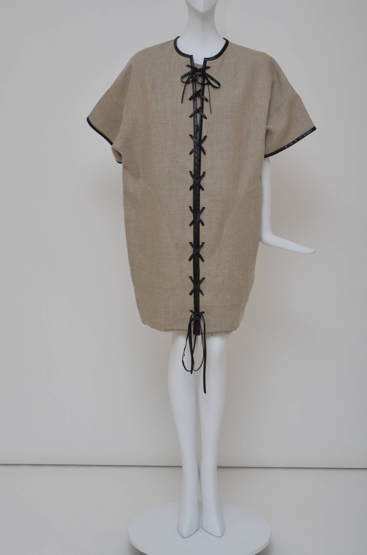 Robe Céline en lin avec manches dolman:: garnie de cuir noir:: deux poches fendues à la taille:: bord brut à l'ourlet et fermeture à lacets sur le devant avec détails en laiton vieilli. 
Condition : neuf avec étiquettes. 
Mesures : Poitrine 44