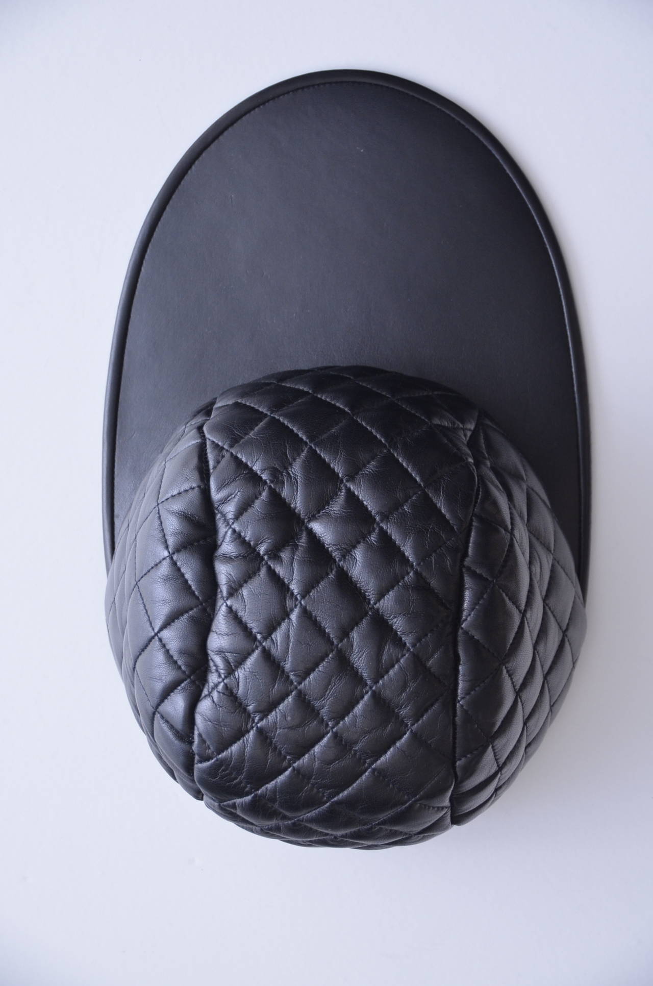 Chanel vintage lambskin leather  quilted hat.
New with tags.
Very unusual hat with super  long front .

As seen on Linda Evangelista and Karl Lagerfeld's Hip-Hop-Inspired Fall 1991 Chanel Show.

Size 56 (marked small on the paper tag) but its