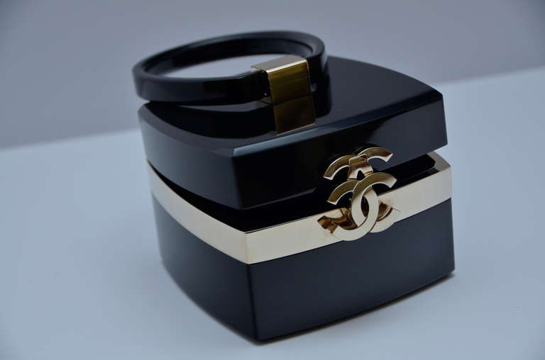 Black lucite Chanel box shape clutch with gold-tone accents, 'CC' push lock closure at front, leather lining and mirror at interior top. 
From fall collection 2004.Excellent mint condition.
Inside mirror and lambskin lining.
Extremely rare 