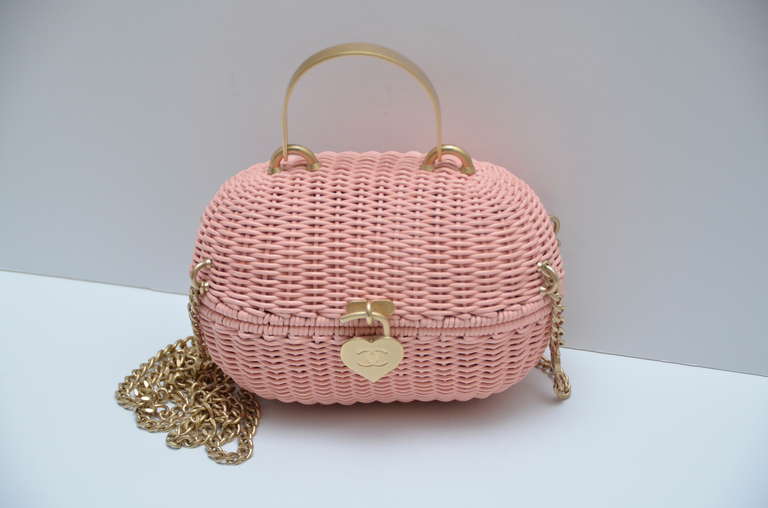 Excellent like new Chanel pink mini straw handbag.
This Highly Collectible Authentic Chanel Sweetheart Pink Handbag was designed in 2005.it is called the Divers Sac. It is a straw woven wicker basket with a heart shaped closure. All the hardware is