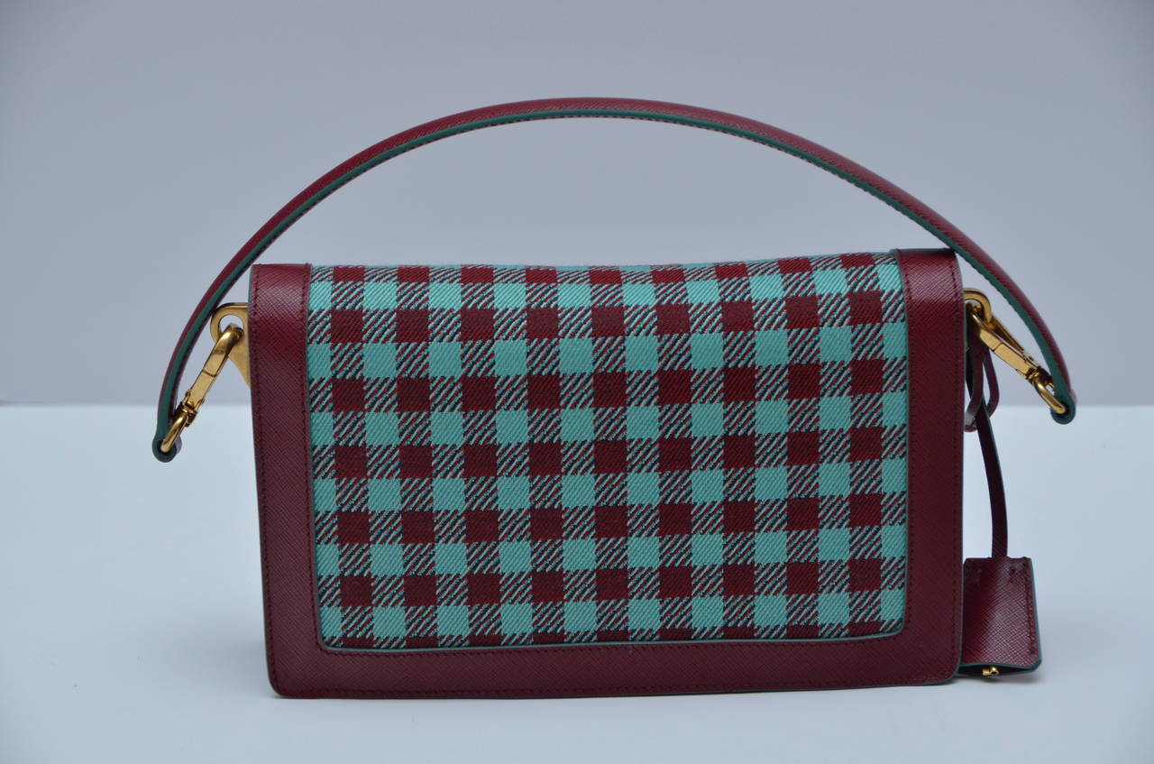 Prada handbag  saffiano  burgundy leather mix with checkered fabric.
Two way shoulder handbag.Could be carried over the shoulder or cross body.
Removable strap.Beautiful,stylish and useful handbag.
Inside lined in burgundy saffiano leather and