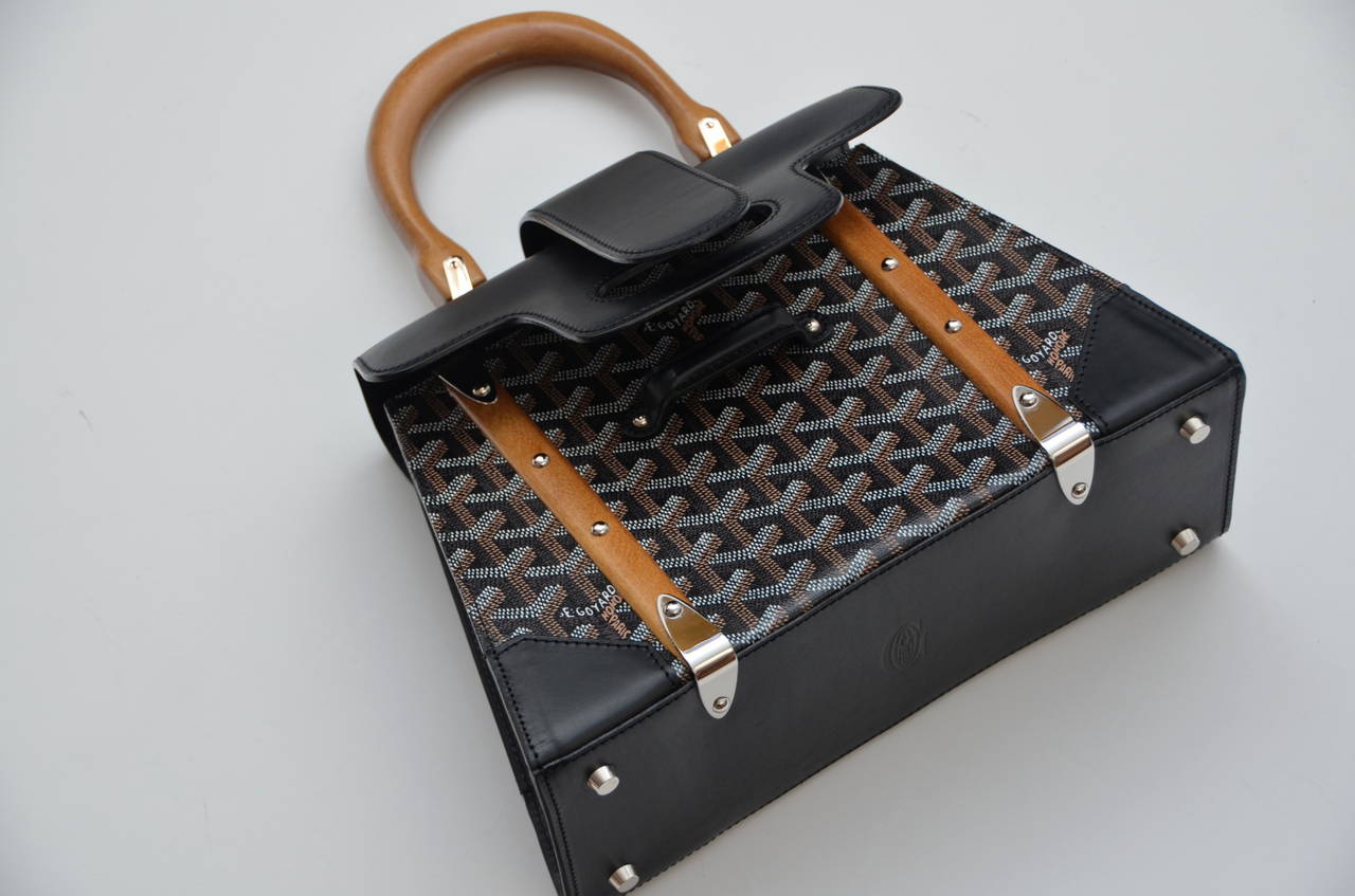 Goyard Celebrities favorite monogram handbag .
Goyard print with black leather flap, wooden handle and strips with silver toned hardware. Tangerine interior has one zip pocket. 
Includes original dust bag. 
Condition:New without