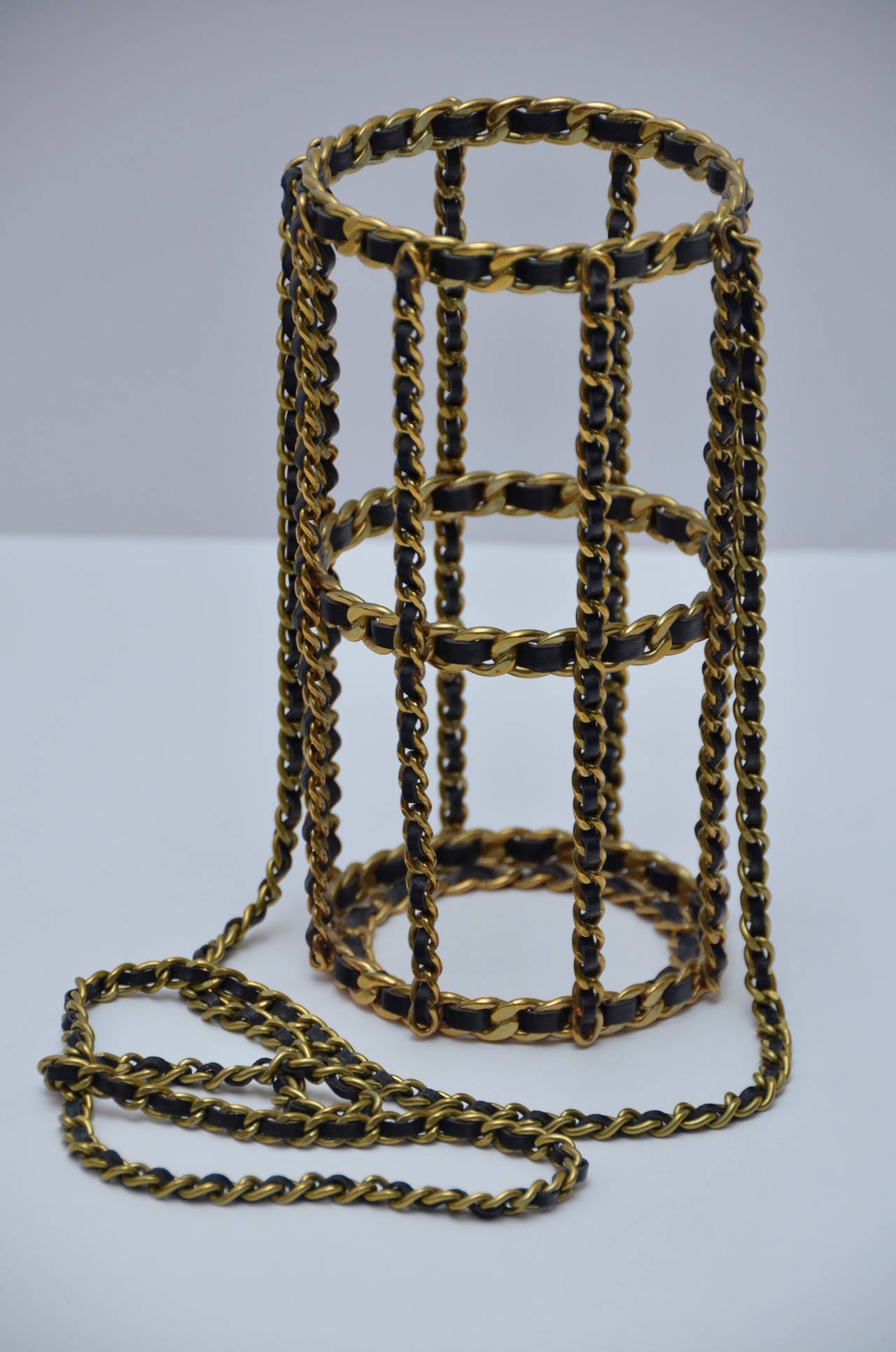 This CHANEL Water Bottle Holder is made of golden metal with black leather. 
1994 Autumn/Winter collection. Made in France. 
Gold tone metal woven with black leather. Approximate measurements: Height: 7.75