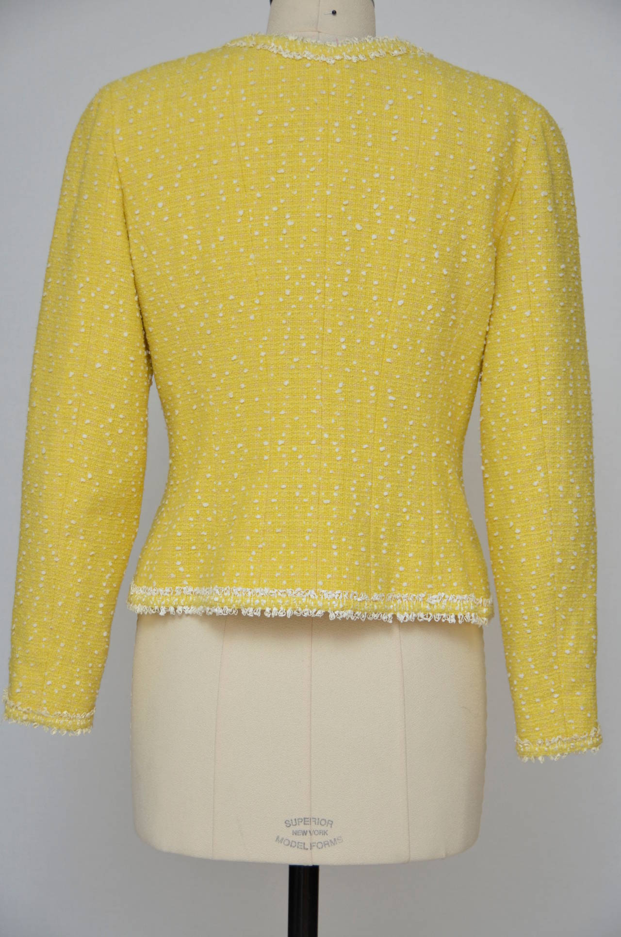 Quintessential Chanel, but in an unexpected bright pop of yellow! This Chanel Boutique  jacket is from Spring 1997.
Cotton/wool blend boucle in sunny lemon yellow with slubs of white in the weave. The fitted jacket is accented with braid at the